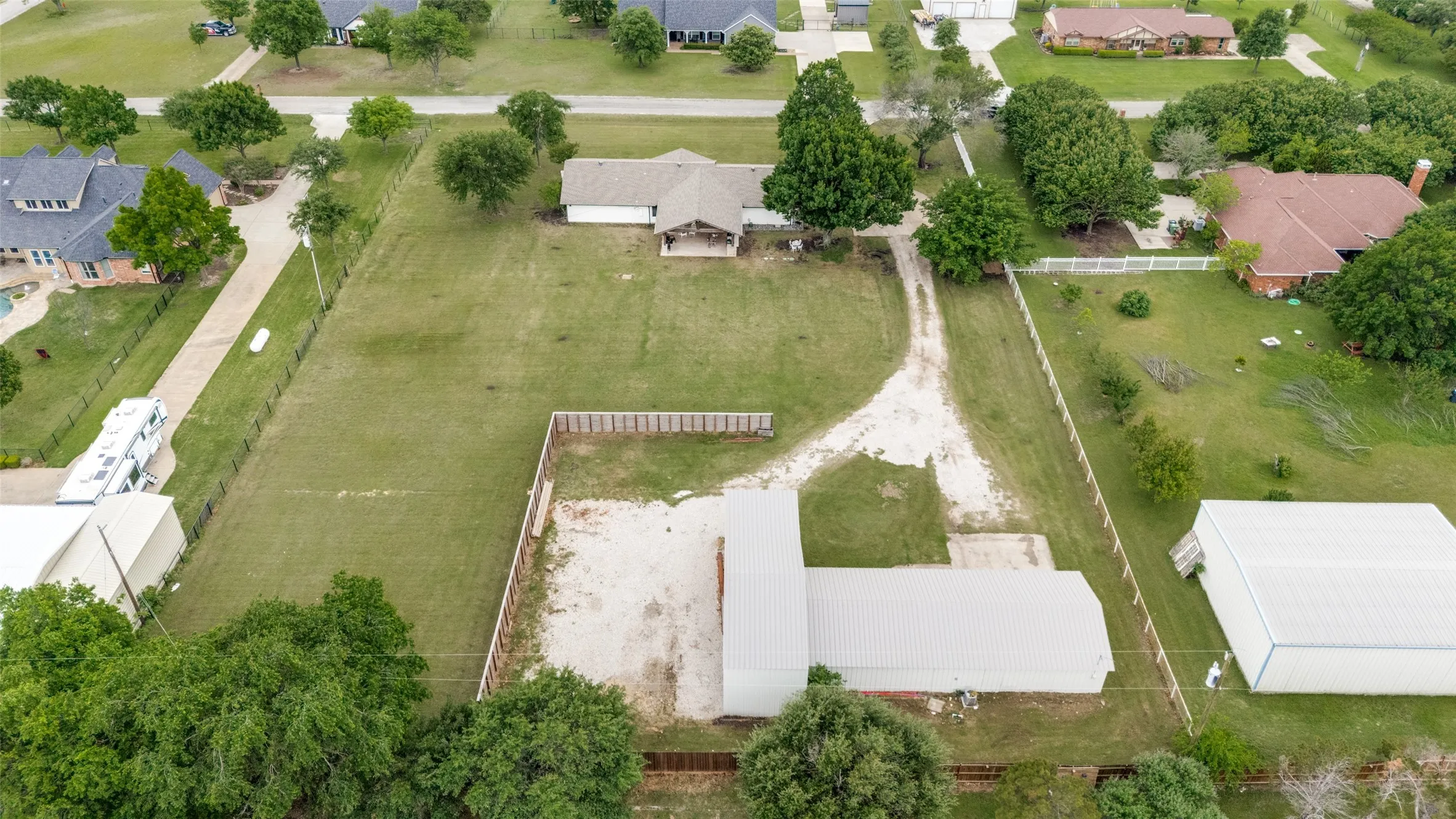 Expansive property featuring a gravel driveway, multiple outbuildings, and a perimeter fence