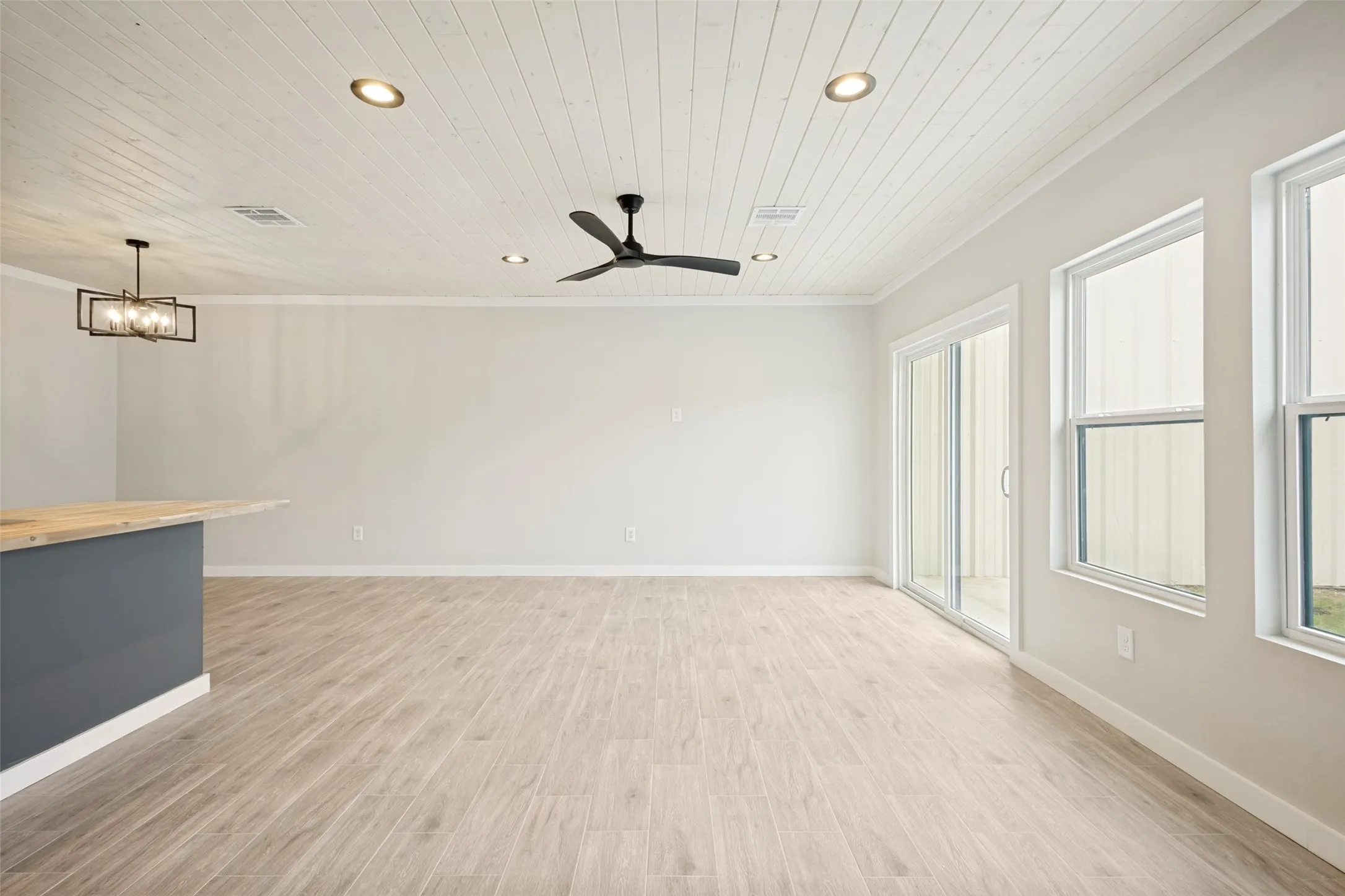 Guest house -Spacious interior featuring light wood-finish flooring, a contemporary black ceiling fan, recessed lighting, and a linear chandelier