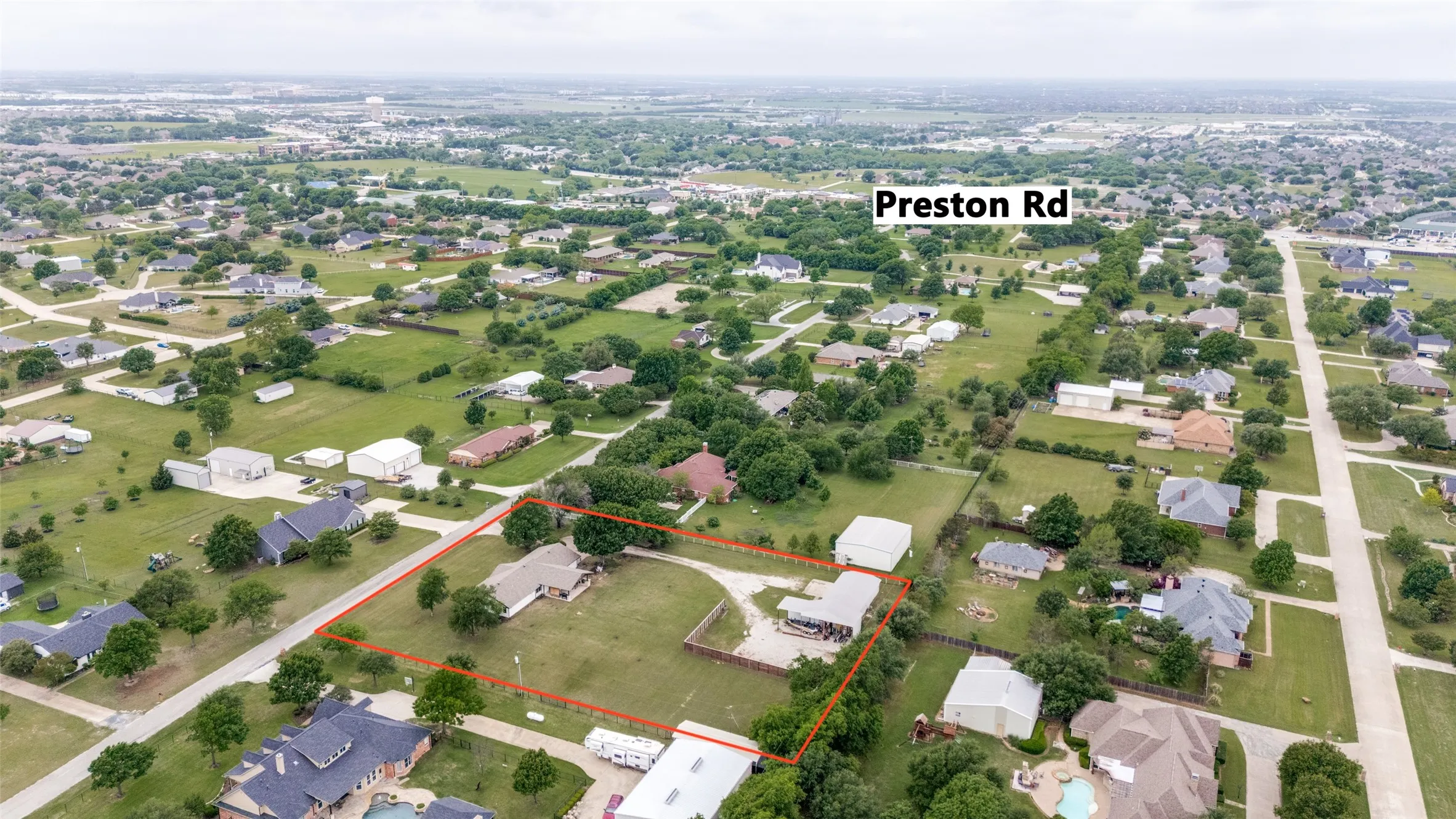 Aerial property overview featuring two residential structures, a detached garage, and a large open yard area