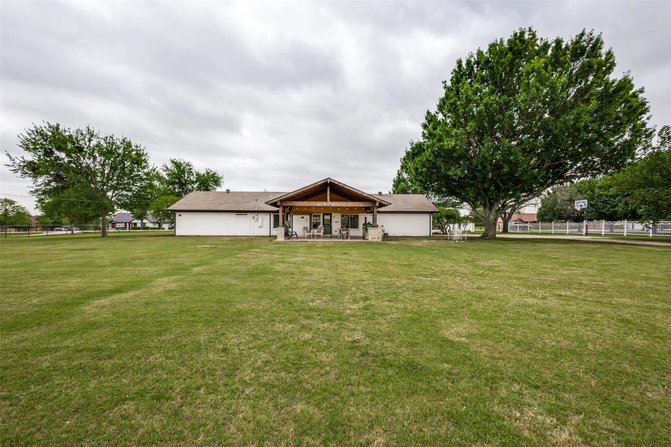 Expansive green lawn with mature trees and a rear patio