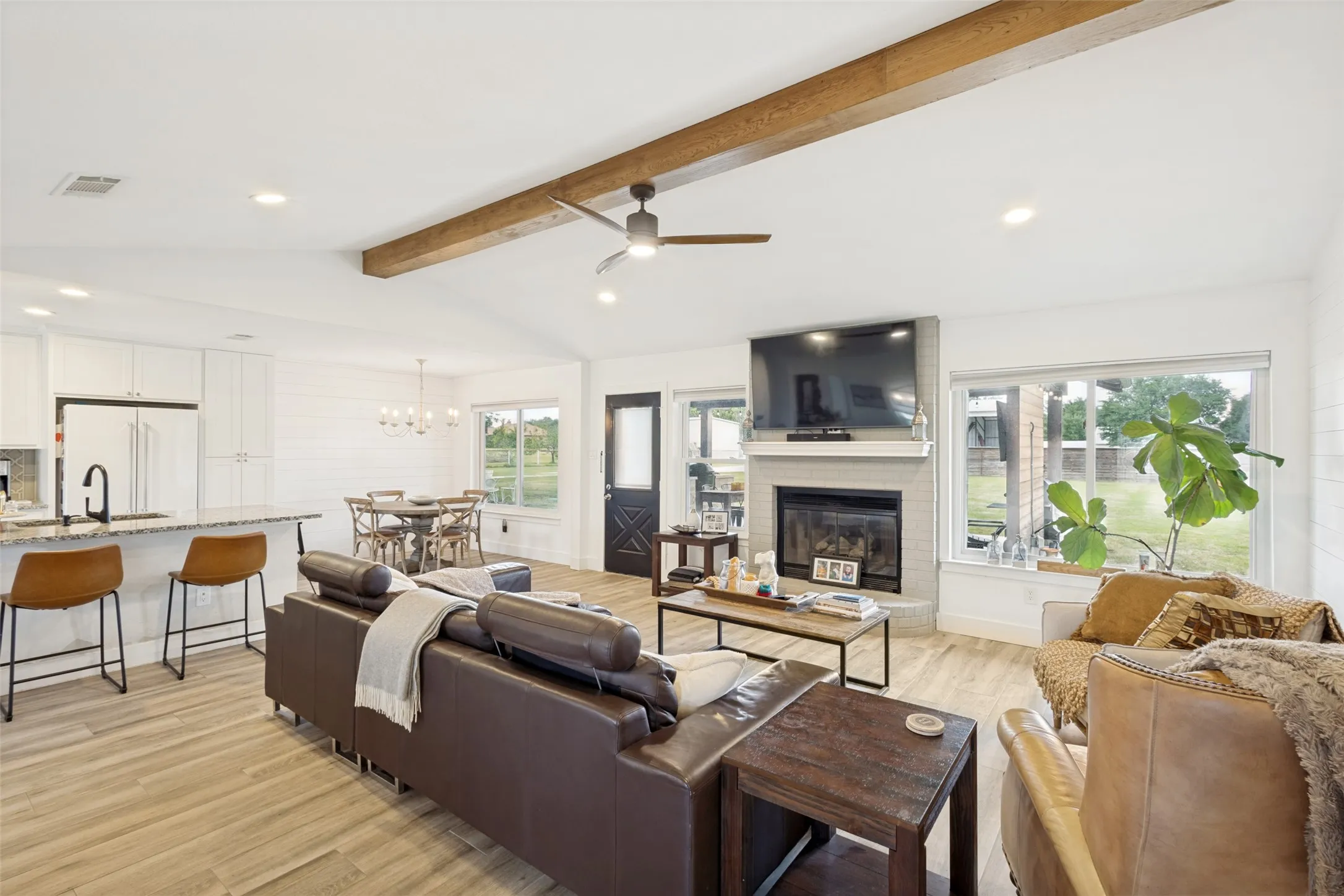 Open-concept living area with vaulted ceiling, exposed wood-finish beam, and recessed lighting