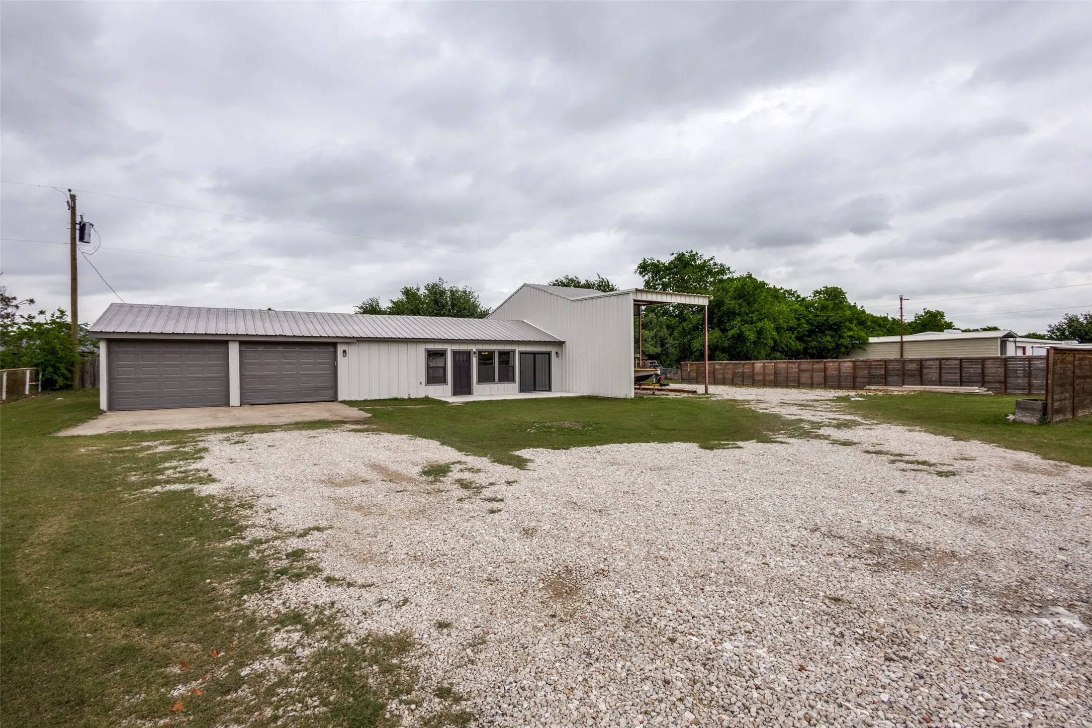 Guest house - Single-story residence featuring a metal roof and white vertical siding