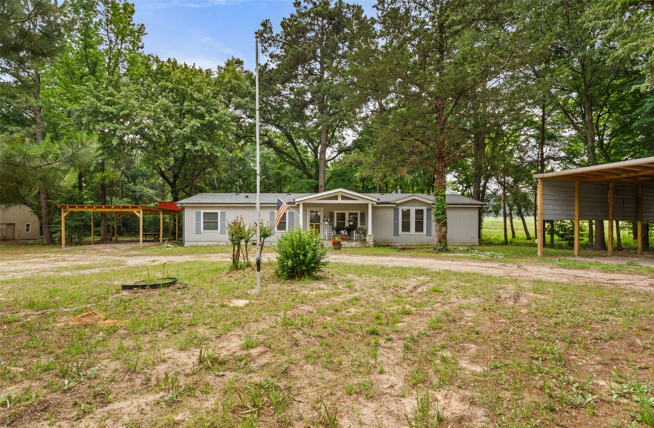 Workshop / Hanger shaped off to the left and 2 car Carport to the left, RV Parking and connections on the side and additional Covered RV Parking to the right.