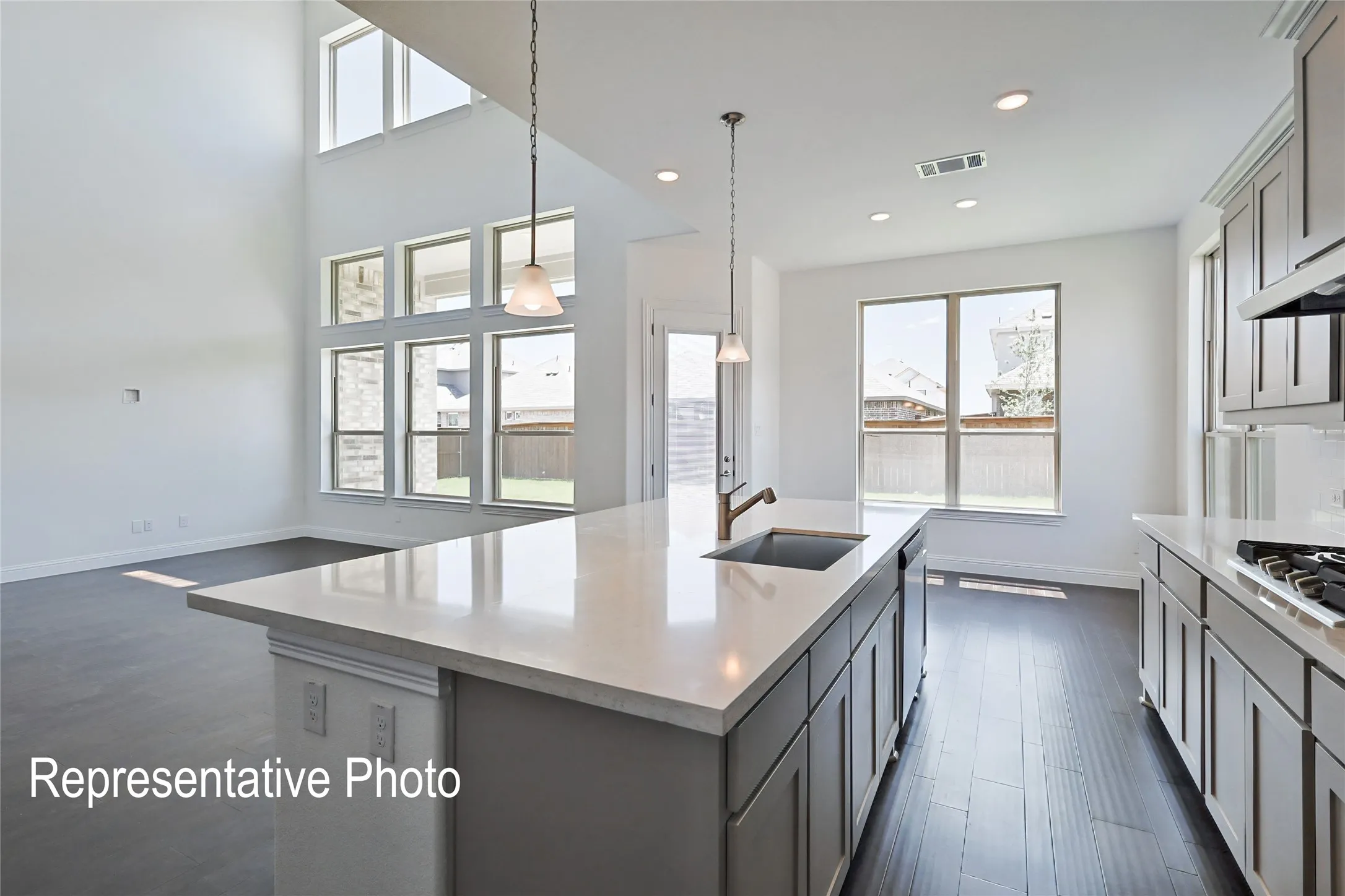 Open concept kitchen featuring a large island with an undermount sink, pendant lighting, and light-toned countertops