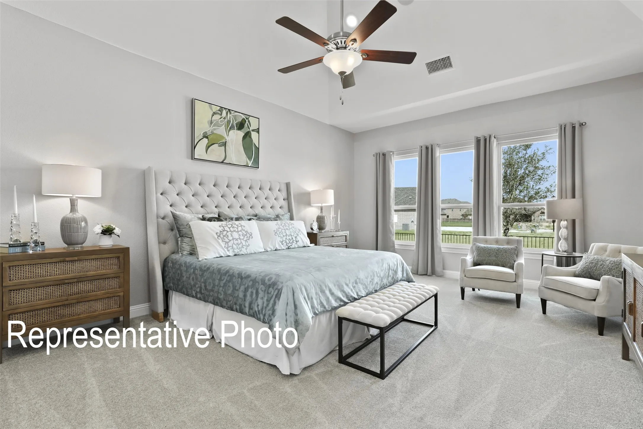 Bedroom featuring light gray carpeting, a tray ceiling, and a ceiling fan with integrated lighting