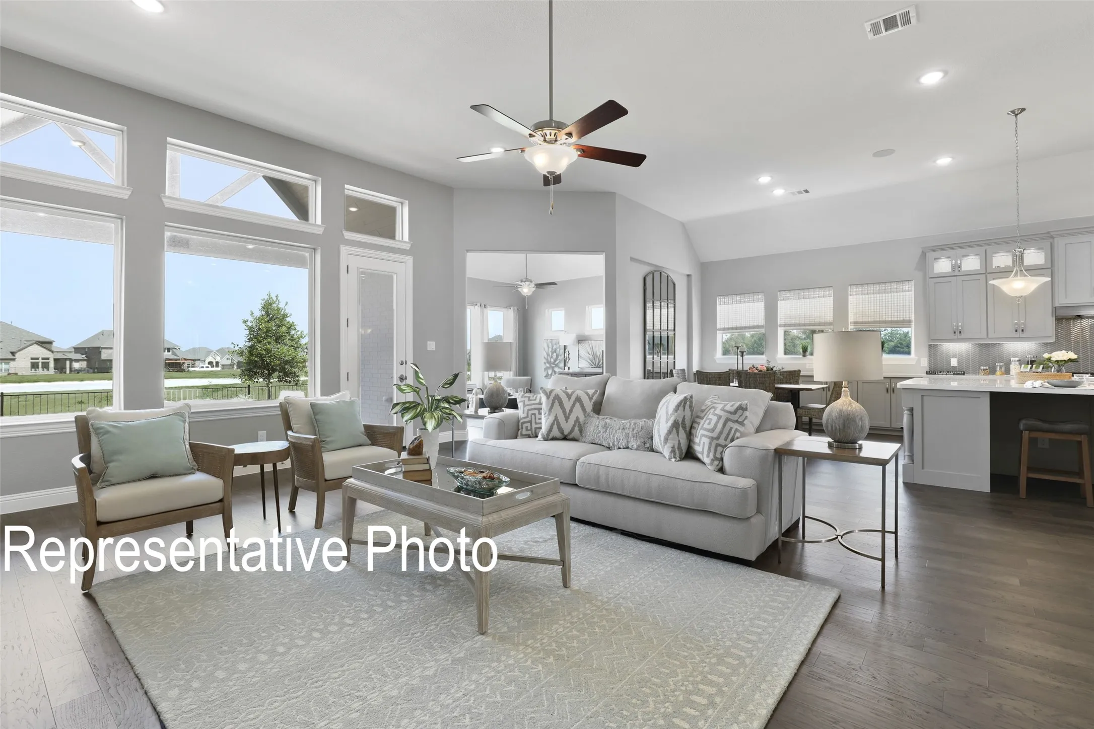Spacious living area featuring expansive windows, recessed lighting, wood-finish flooring, a ceiling fan, and an open-concept kitchen with pendant lighting