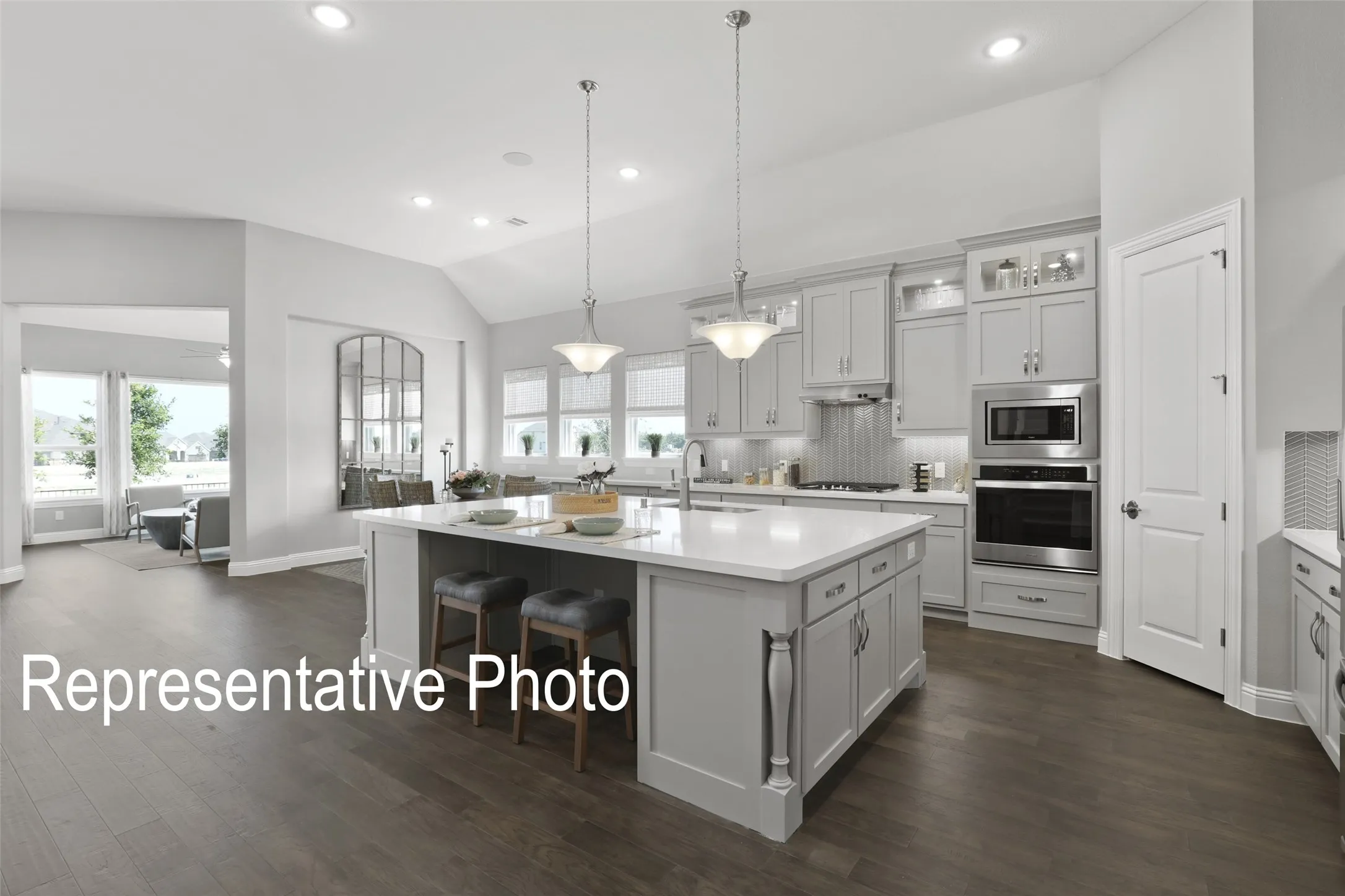 Gourmet kitchen featuring a substantial island with seating, pendant lighting, stainless steel appliances, custom cabinetry, and wood-finish flooring
