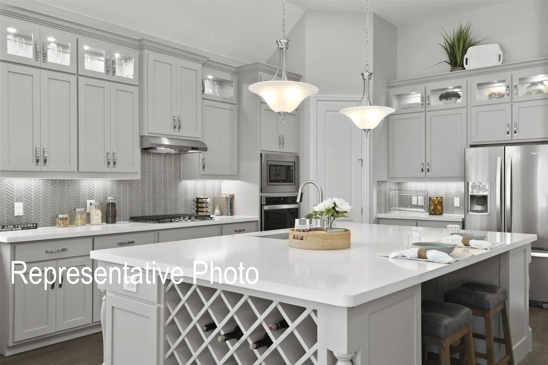 Kitchen featuring light gray cabinetry, stainless steel appliances, a chevron-patterned tile backsplash, and a central island with an integrated wine rack