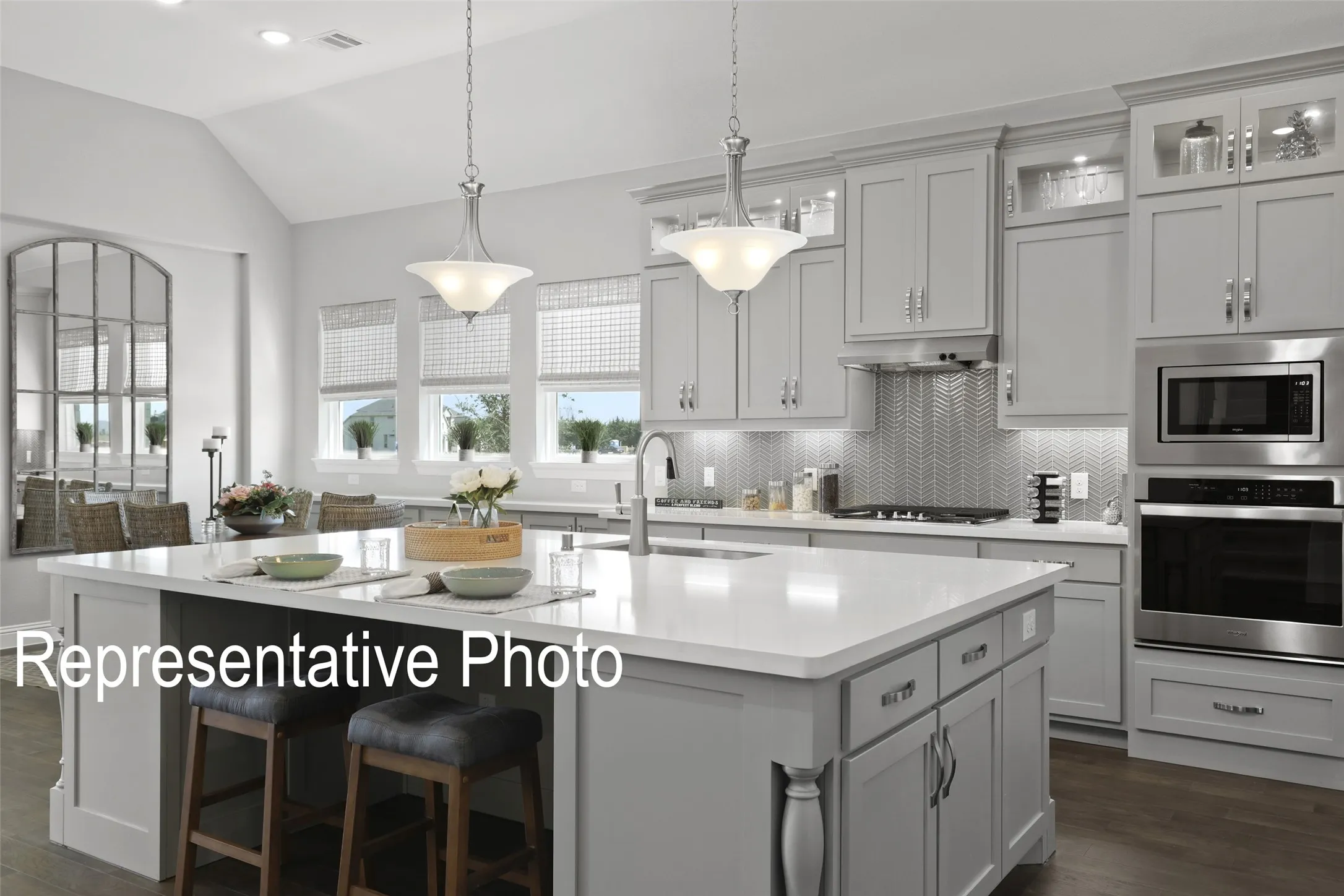 Gourmet kitchen featuring a spacious island, light gray cabinetry, stainless steel appliances, a herringbone tile backsplash, and wood-finish flooring