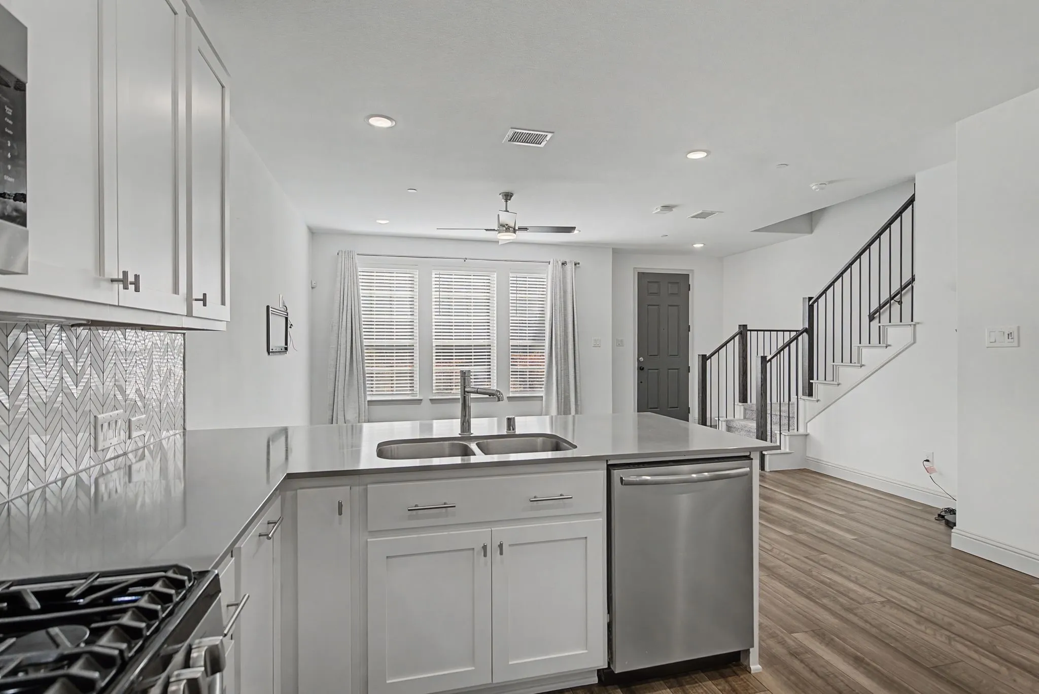 Contemporary kitchen island featuring a double-basin sink, stainless steel dishwasher, and quartz countertop