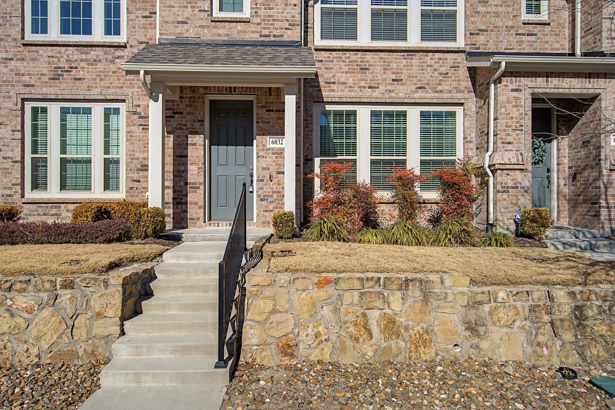 Brick facade with white-framed windows and a covered entryway