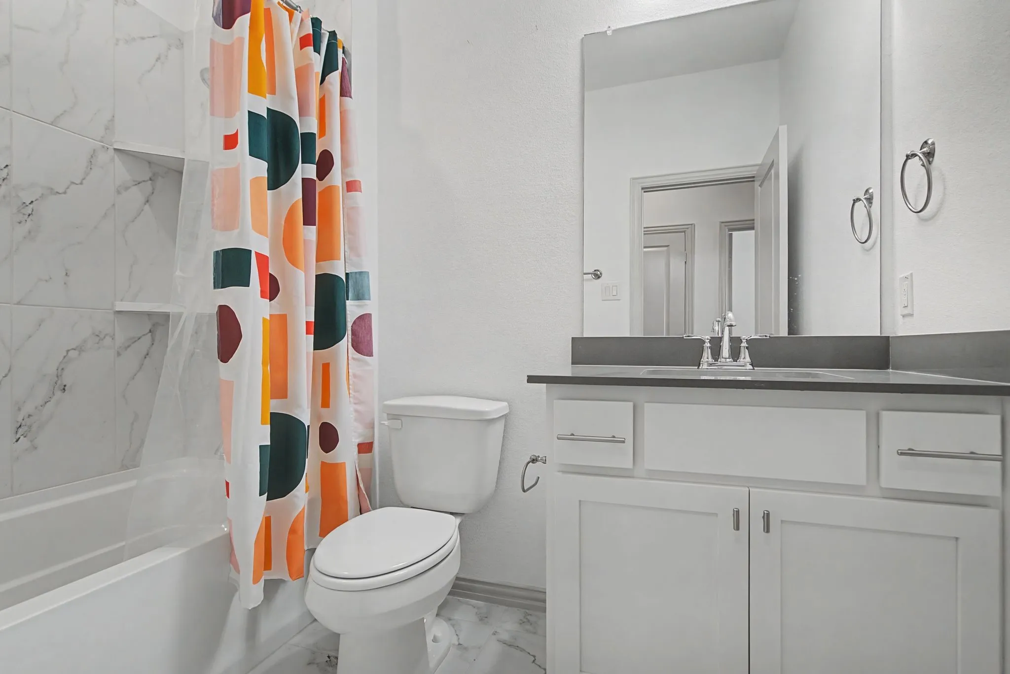Bathroom featuring a white vanity with a dark countertop and undermount sink, a large wall mirror, and a toilet