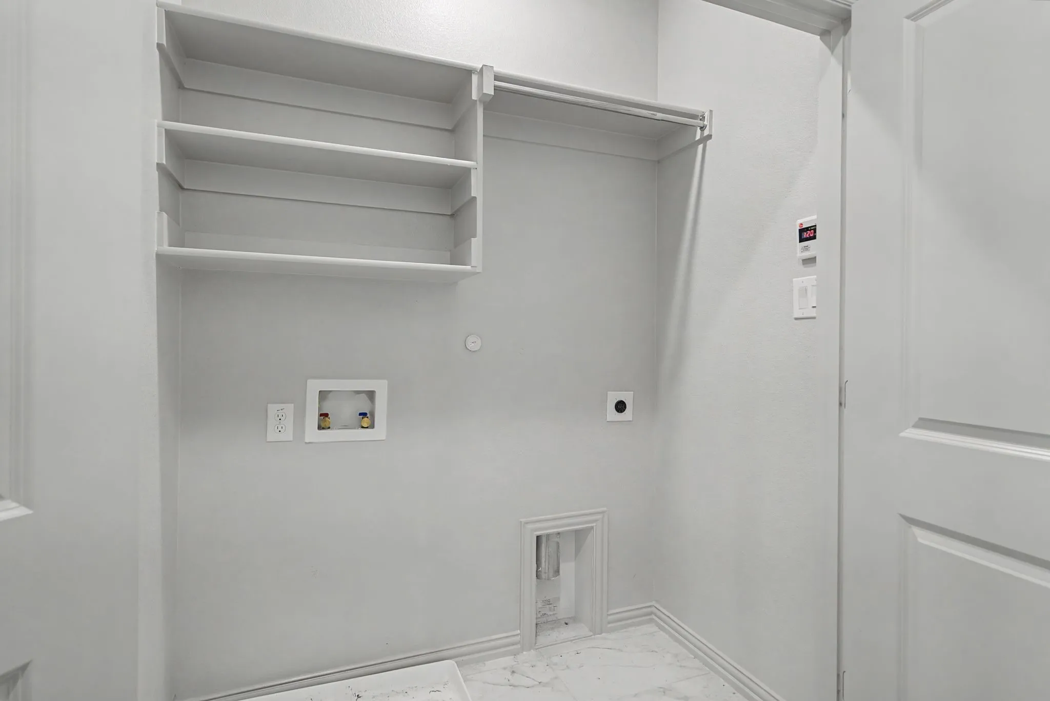 Utility room featuring built-in shelving, a clothes hanging rod, and marble-look tile flooring