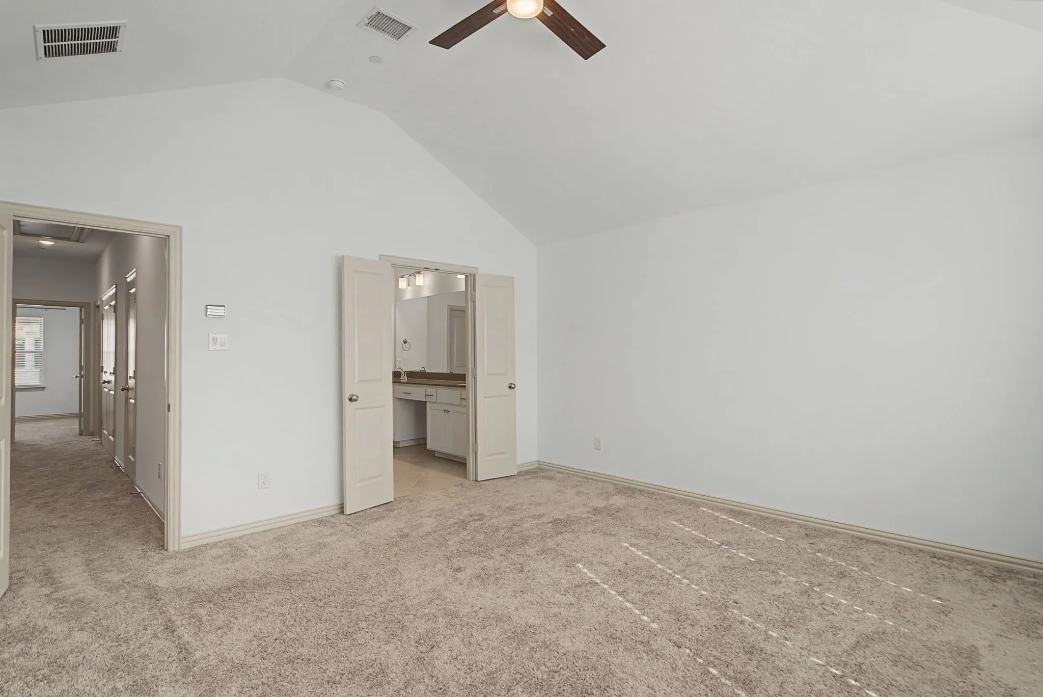 Spacious room featuring vaulted ceilings, light carpeting, and a ceiling fan