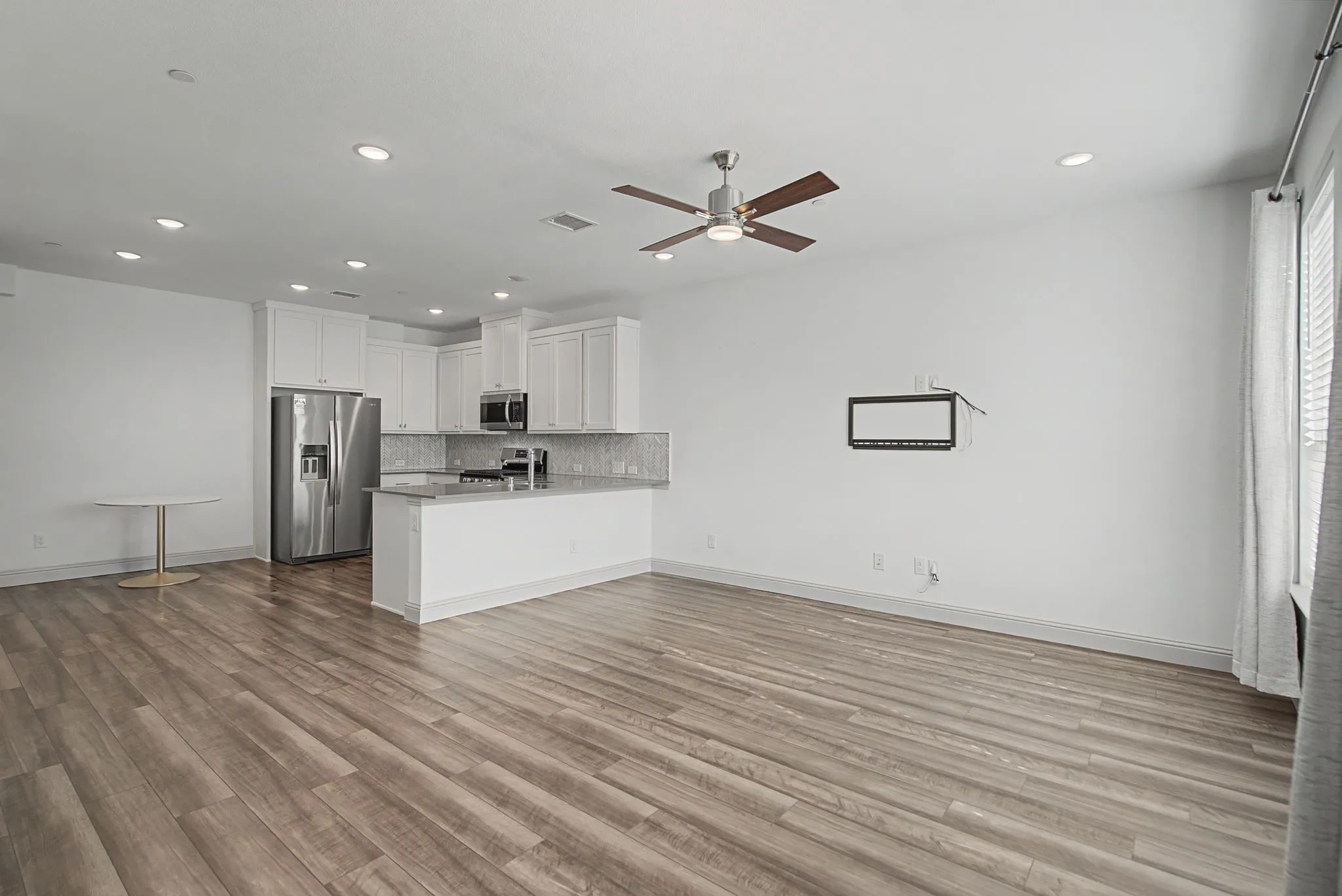 Open-concept living area featuring wood-finish flooring, recessed lighting, and a ceiling fan