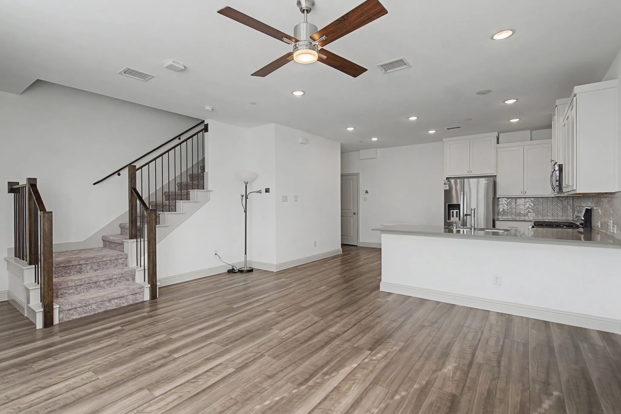 Open-concept living area with wood-finish flooring, a contemporary ceiling fan, and recessed lighting