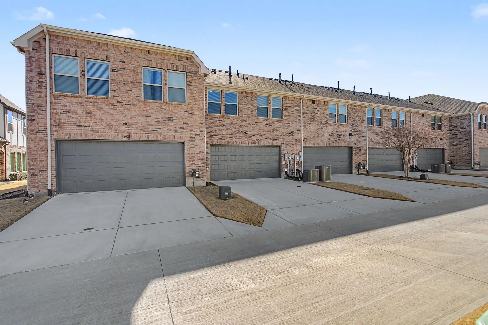 Townhome-style residences featuring brick exteriors, multiple window configurations, and individual garages