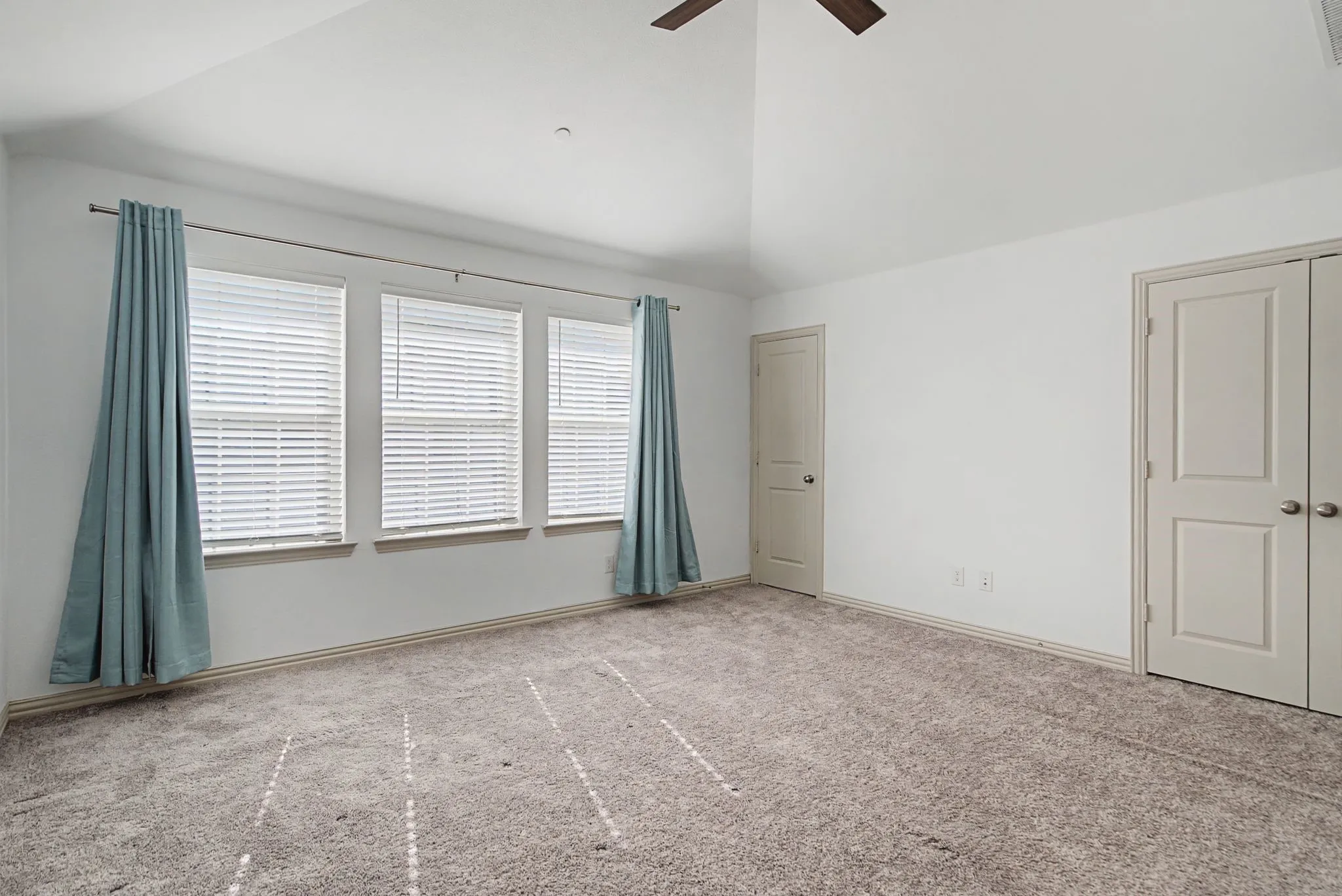 Vaulted ceiling room with ceiling fan and carpet flooring