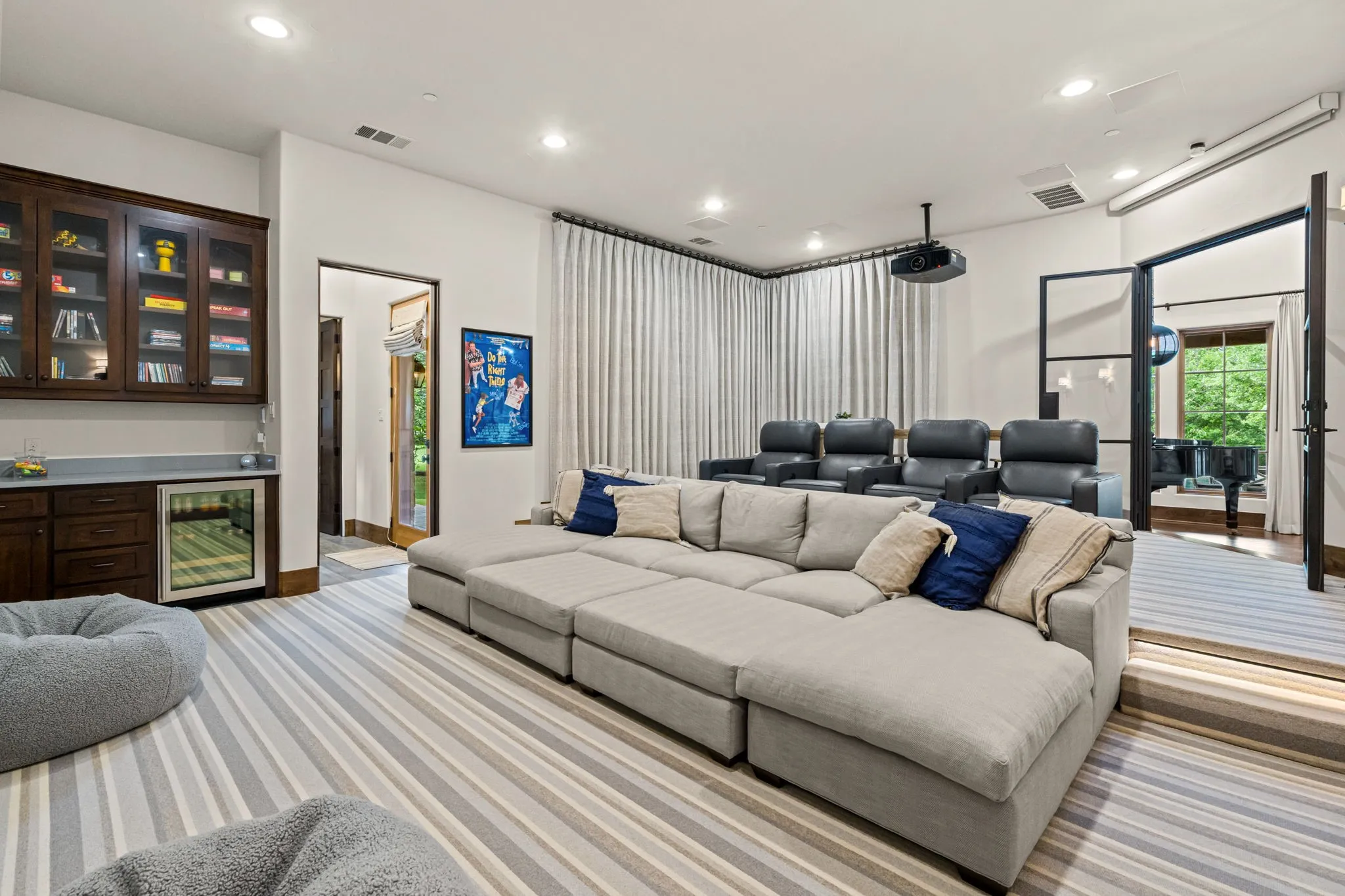 The first floor media room with blackout drapes, electric roll down shades over the iron and glass door and private powder bath