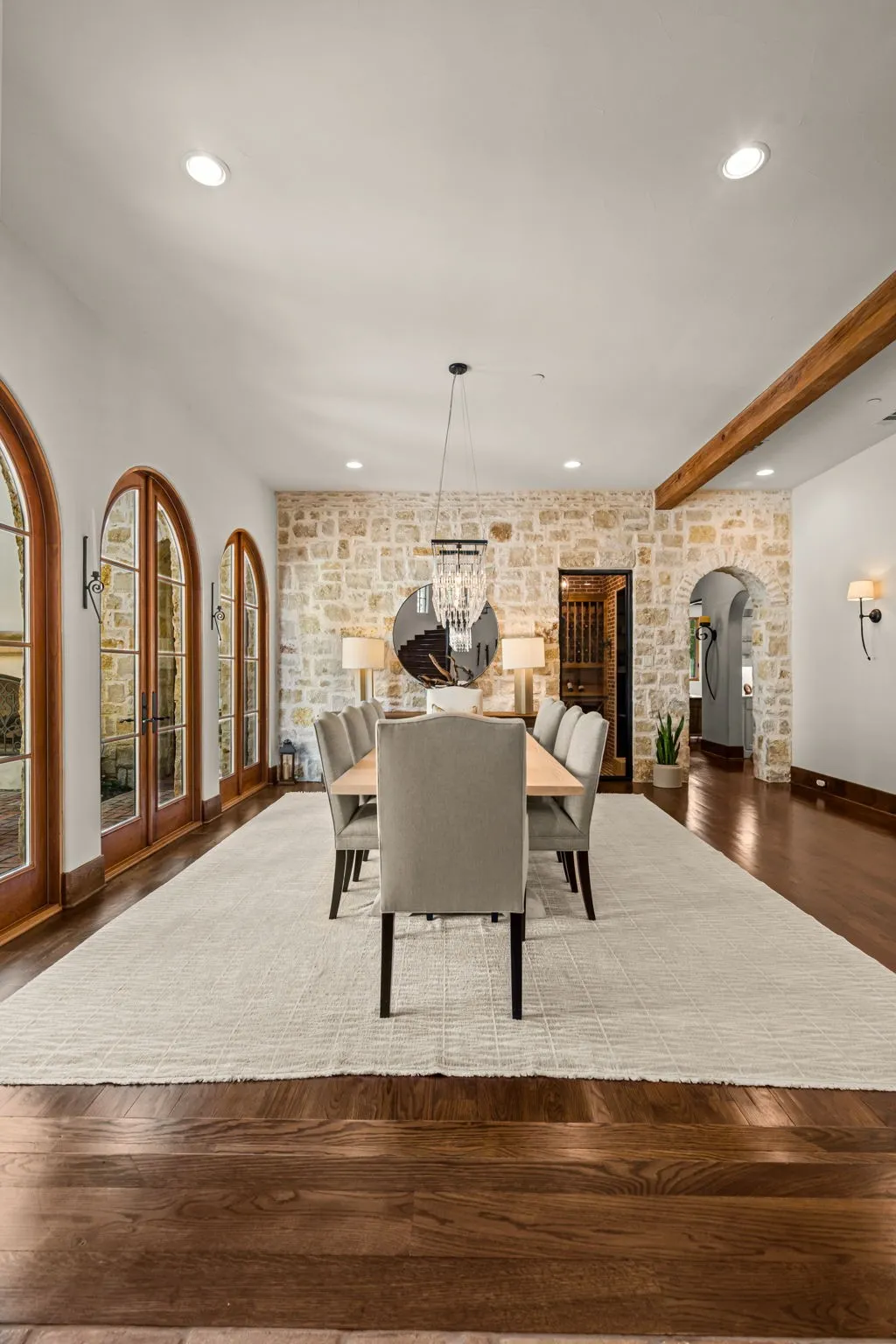 The dining room overlooking the front courtyard thru arched windows and doors and a view into the wine room with brick groin vaulted ceiling
