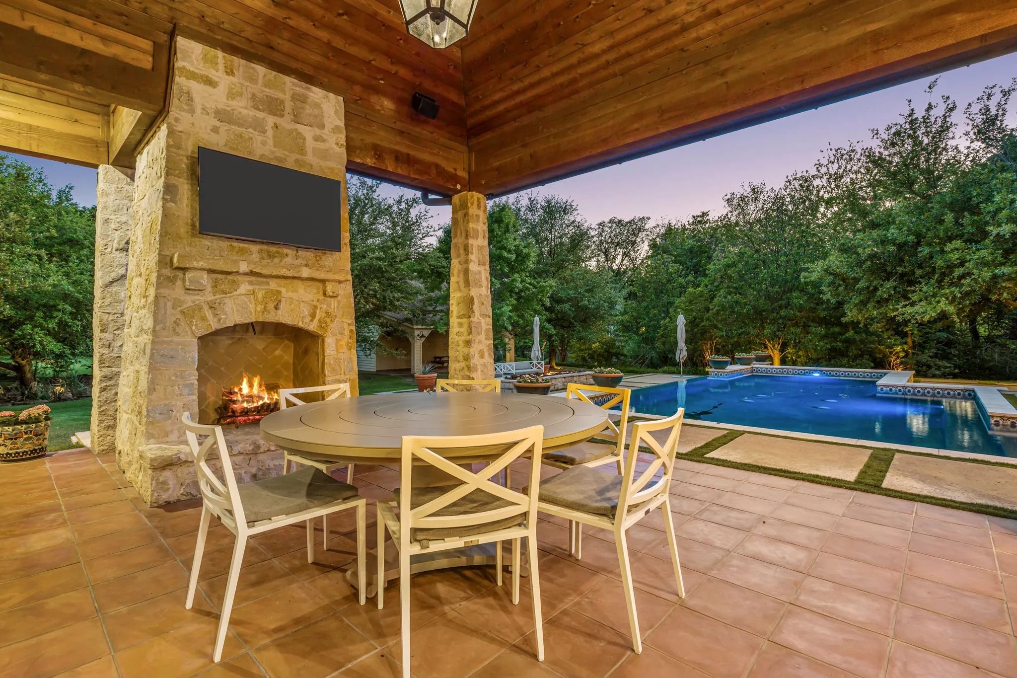 Stone fireplace with gas starter for wood burning overlooking pool