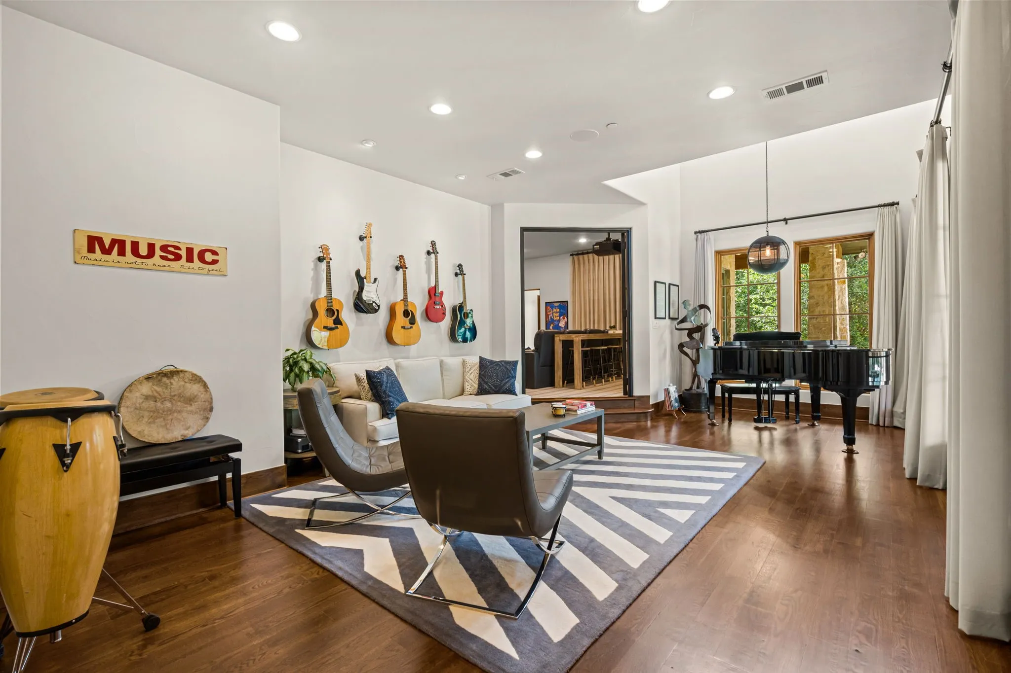 Come thru the iron and glass door into this 1st floor living room being used as a music room - it connects the kitchen to the media room and overlooks the outdoor living and pool.