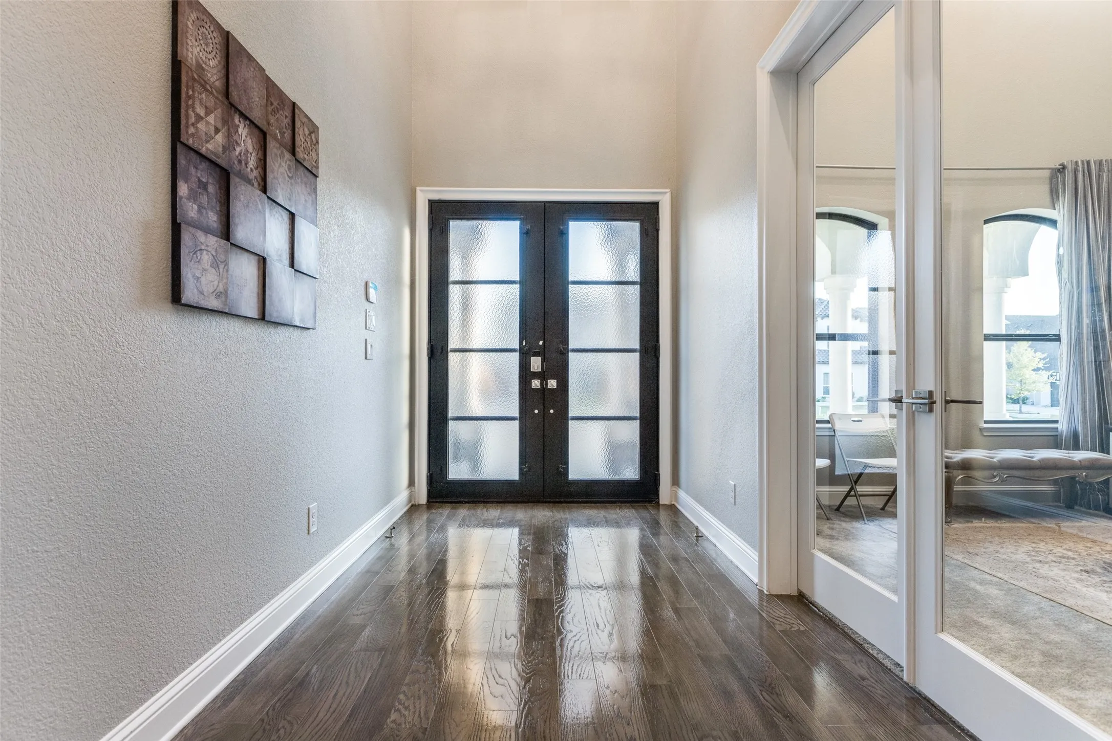 Entryway featuring dark wood-finish flooring, tall ceilings, and a double-door entry with frosted glass panels