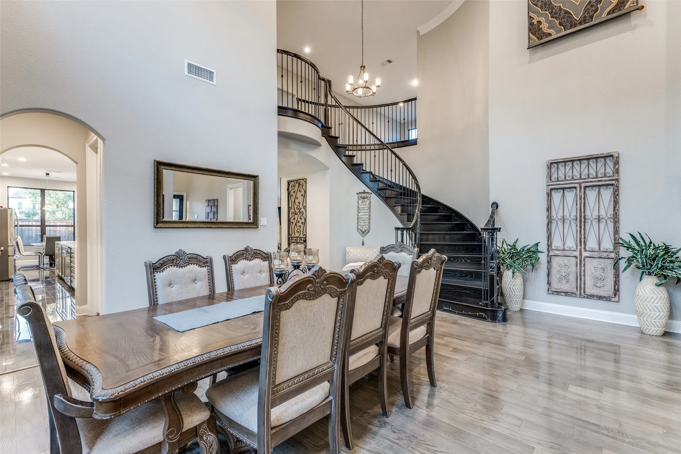Grand two-story entry featuring a curved dark wood staircase with wrought iron balusters