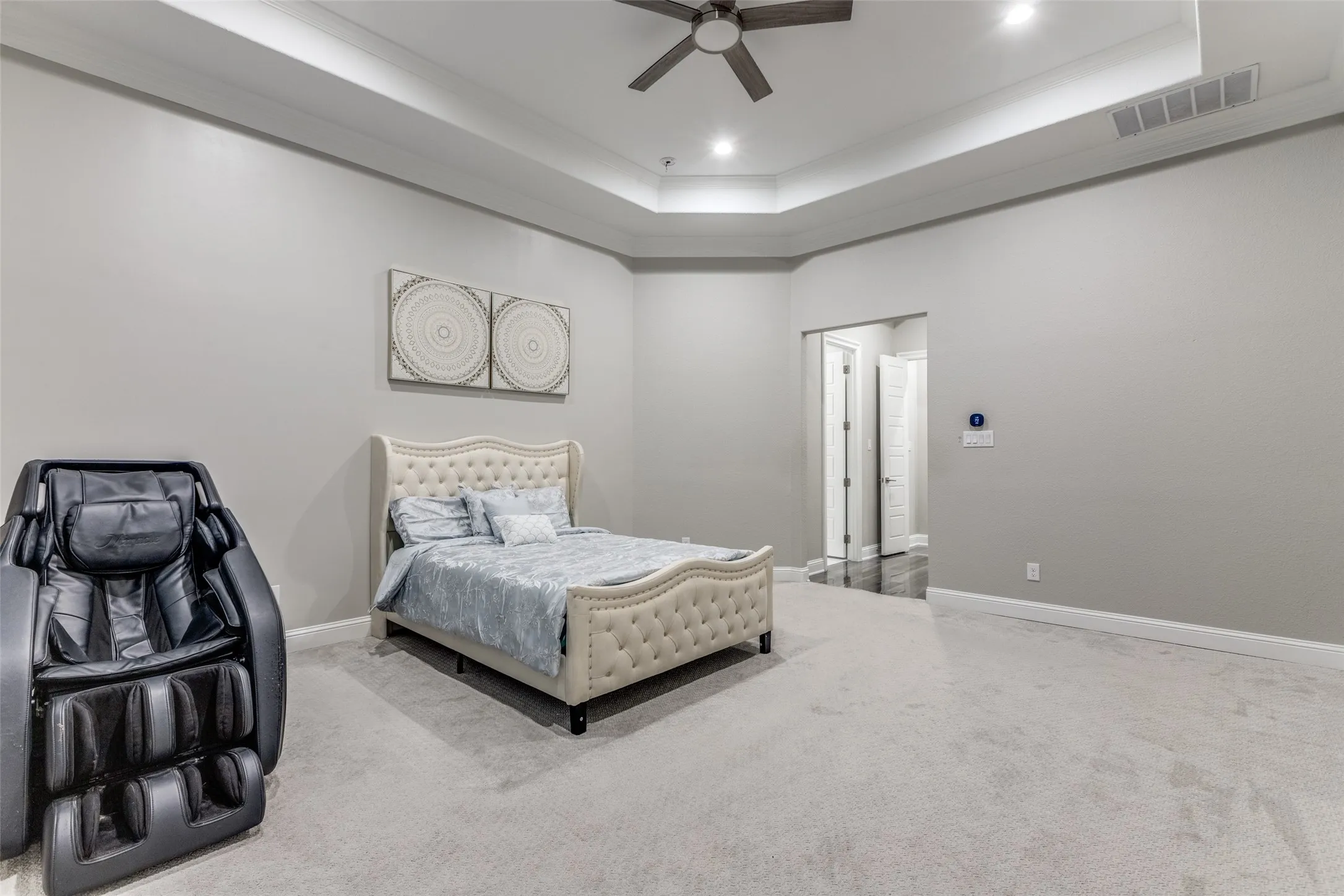 Spacious room featuring tray ceilings with recessed lighting, a ceiling fan, and plush carpet flooring