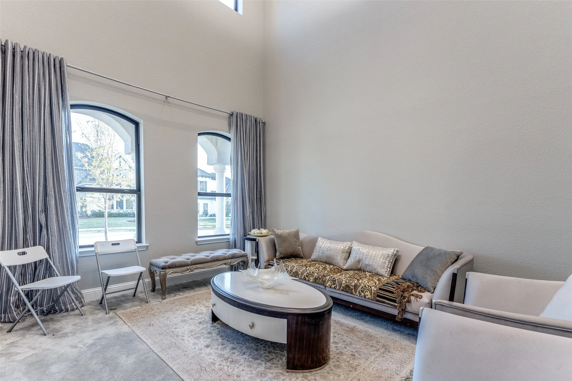 Living area featuring a high ceiling, arched windows, and light-toned walls