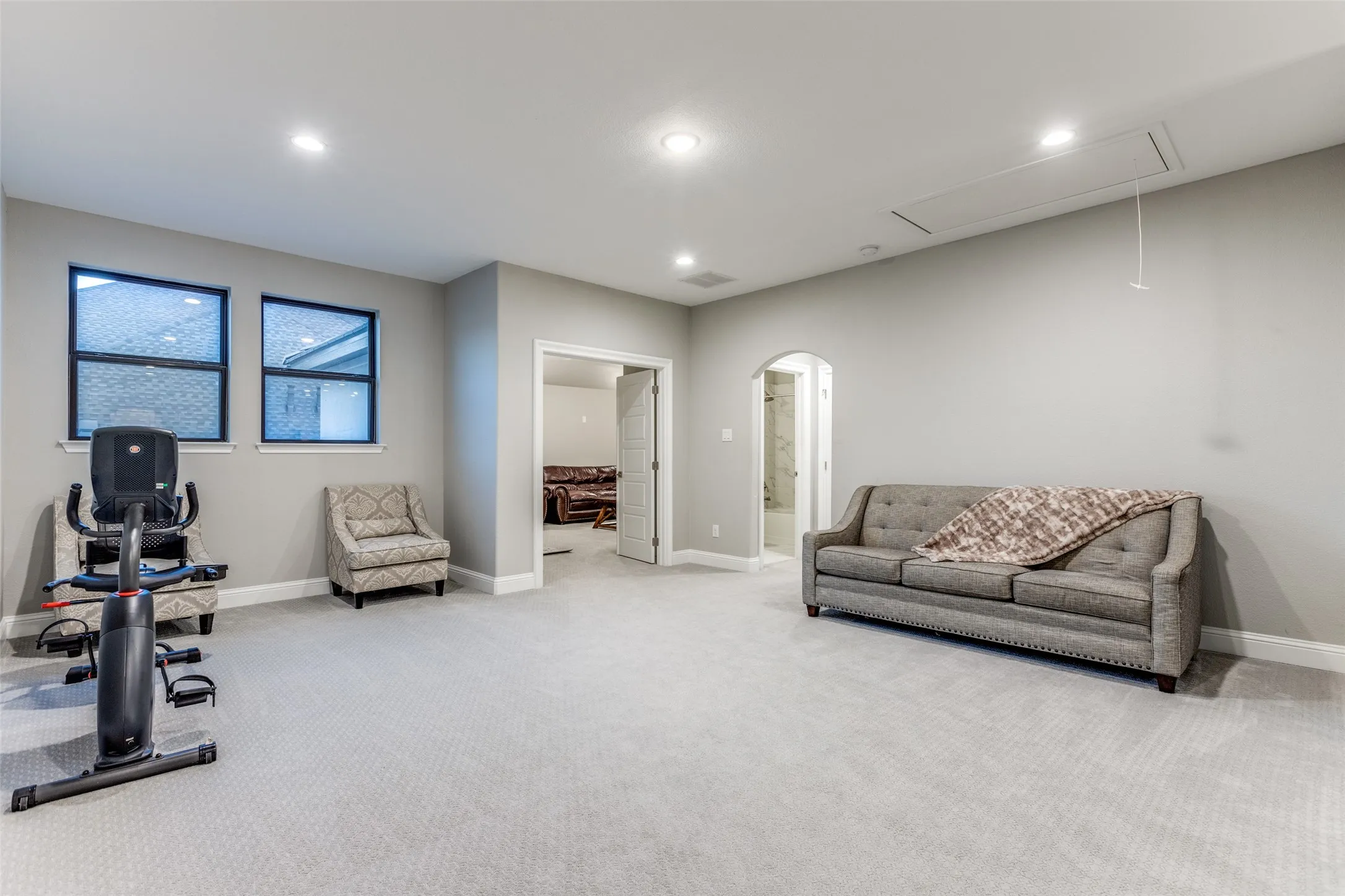 Spacious bonus room featuring light-colored carpet flooring, recessed lighting, double windows, an arched doorway, and an interior door