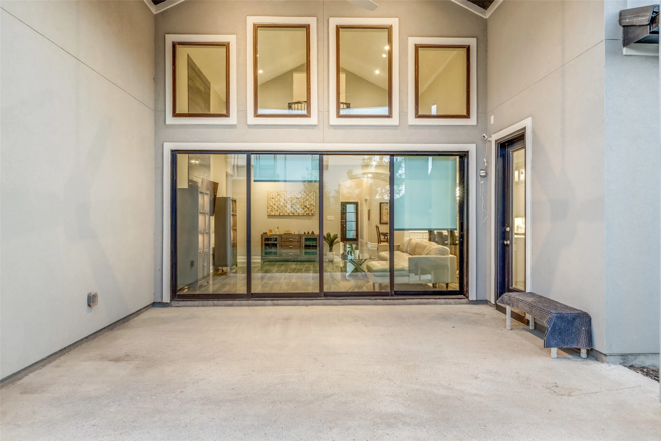 Outdoor patio with concrete flooring, framed by a stucco exterior