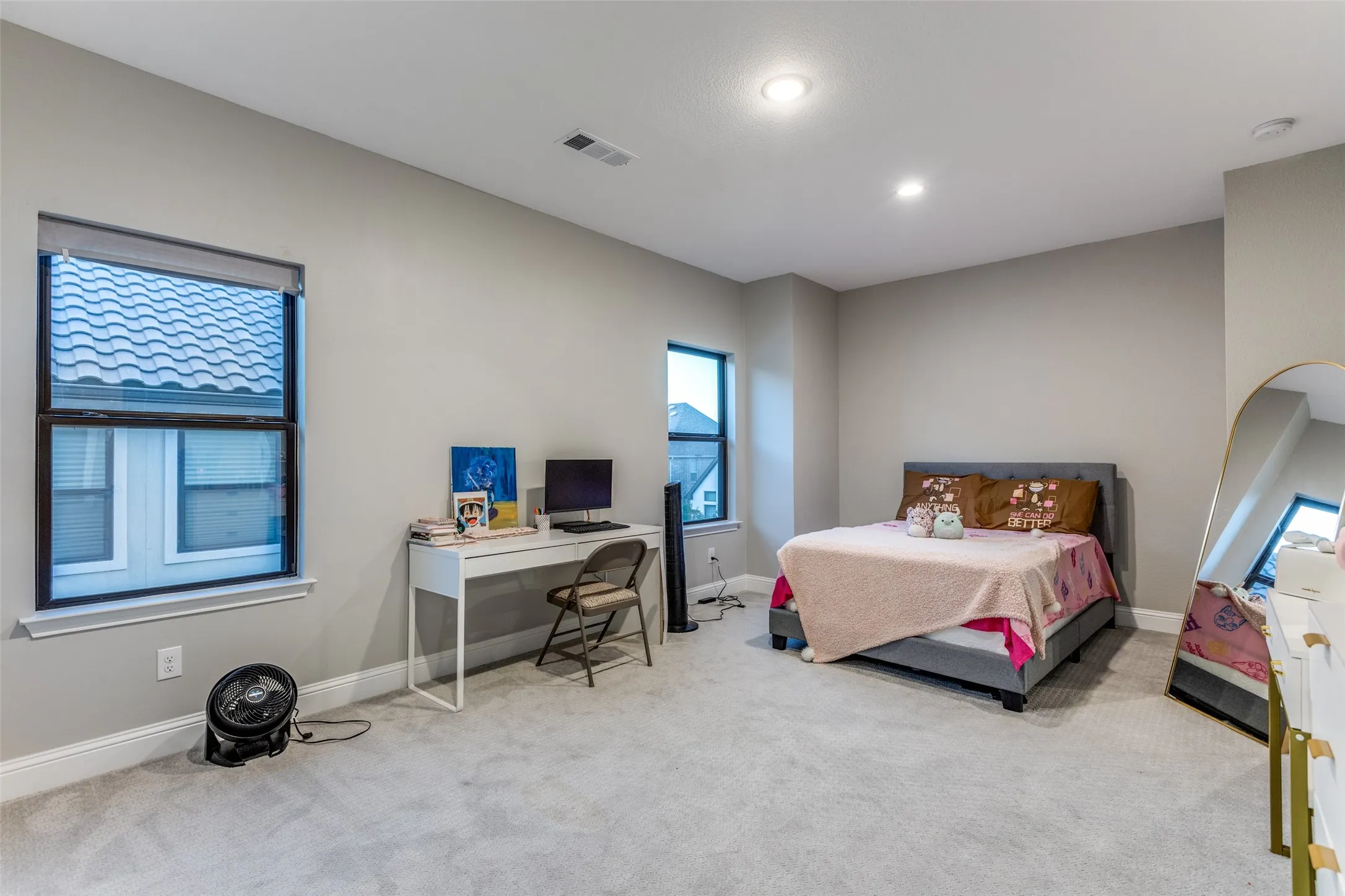 Spacious room featuring light gray walls, light gray carpet, and multiple windows