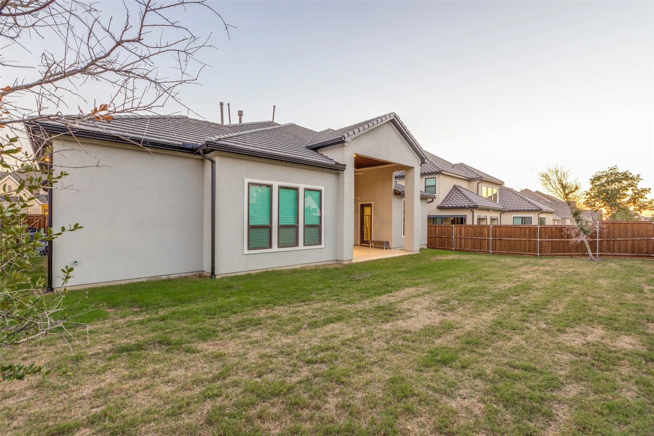 Expansive backyard featuring a stucco exterior, covered patio, tile roof, and privacy fencing