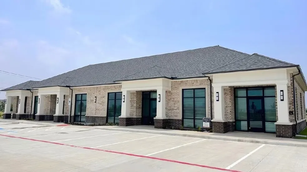 Contemporary commercial building featuring a light brick facade and dark gray shingle roof