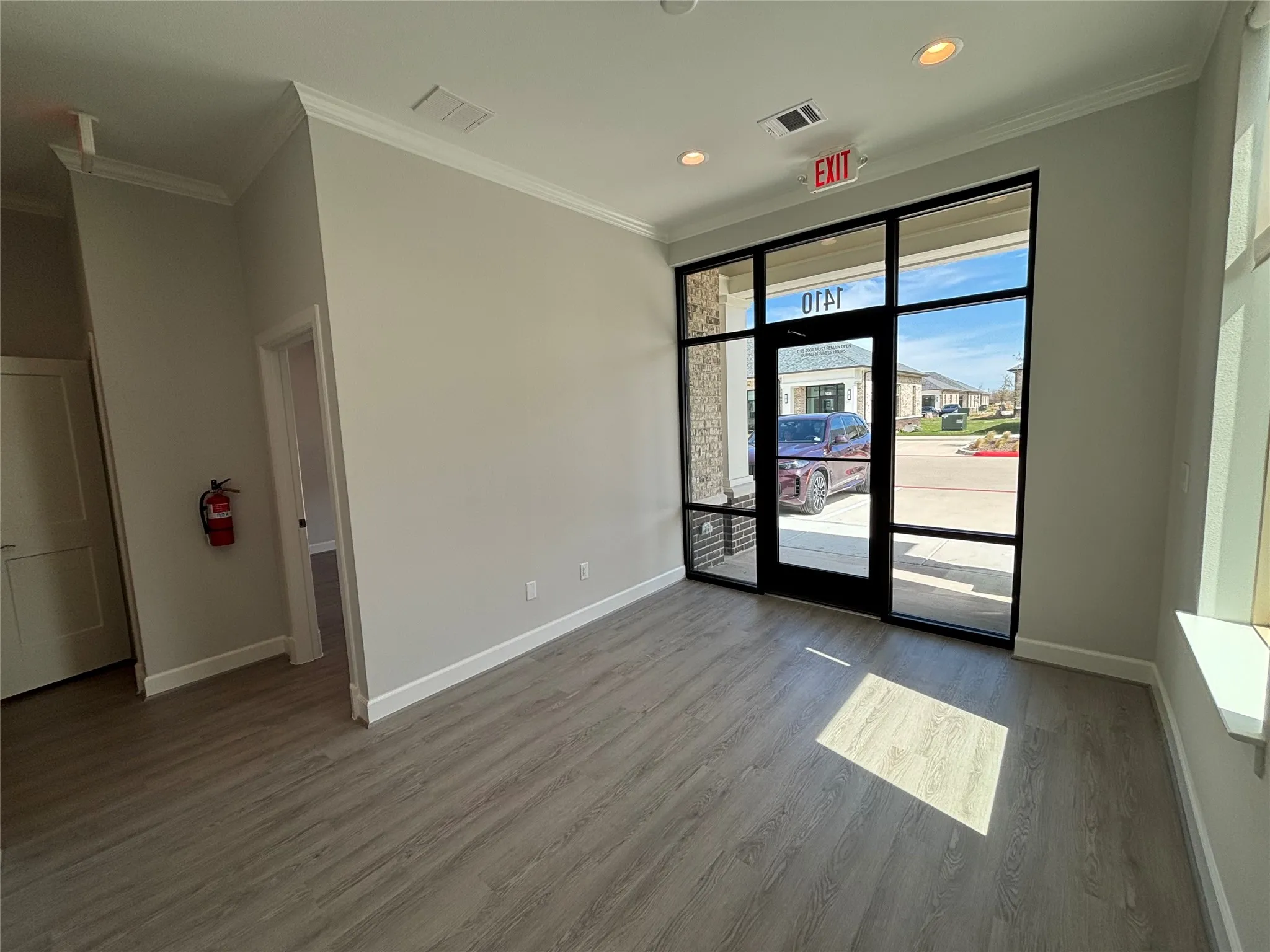 Spacious interior featuring wood-finish flooring, light grey painted walls, and crown molding