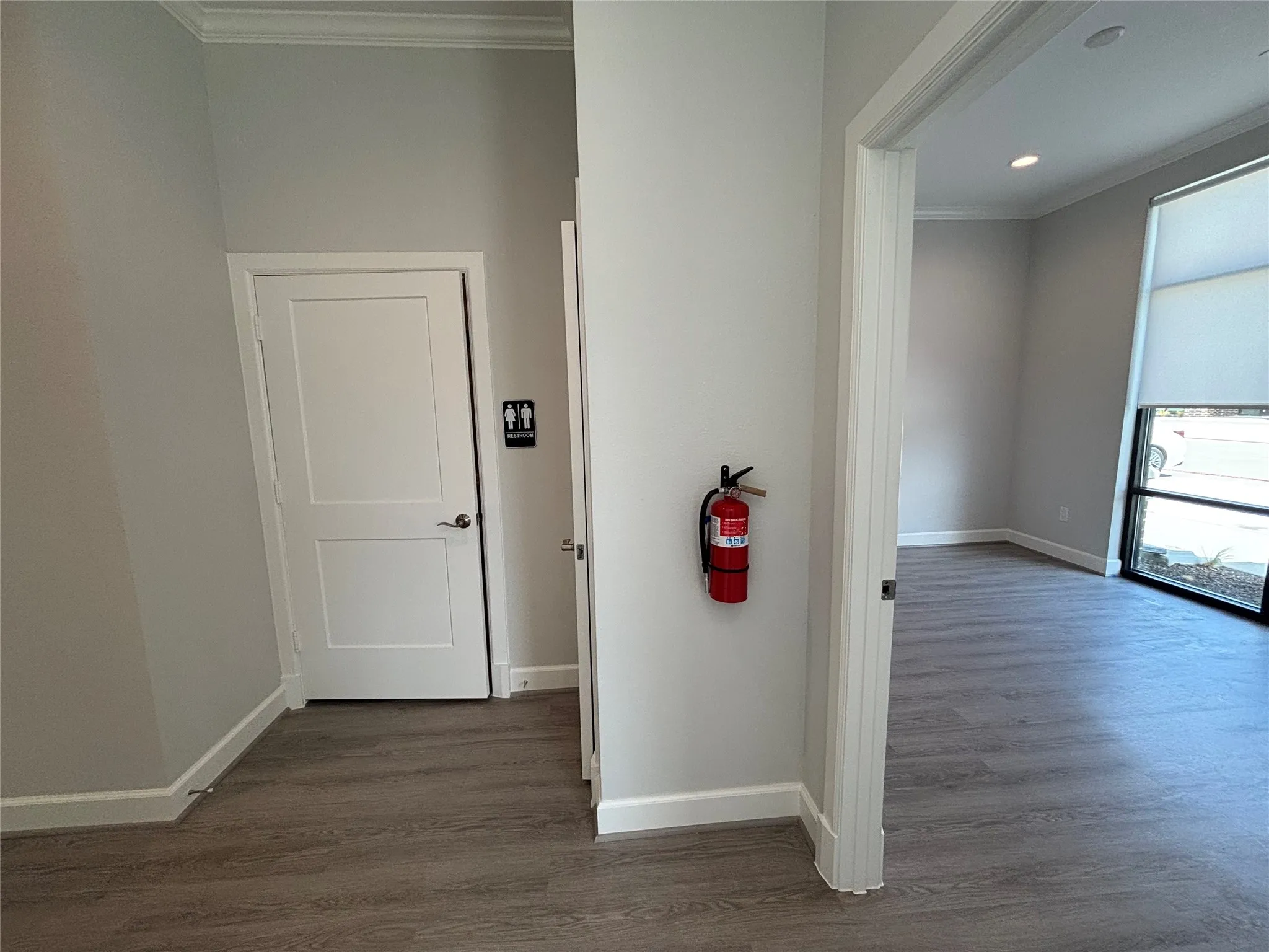 Interior space featuring wood-finish flooring, white baseboards, and crown molding