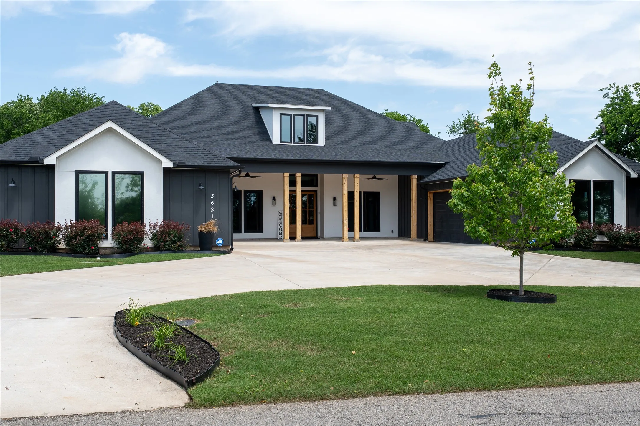 Modern farmhouse exterior featuring dark vertical siding and white gables