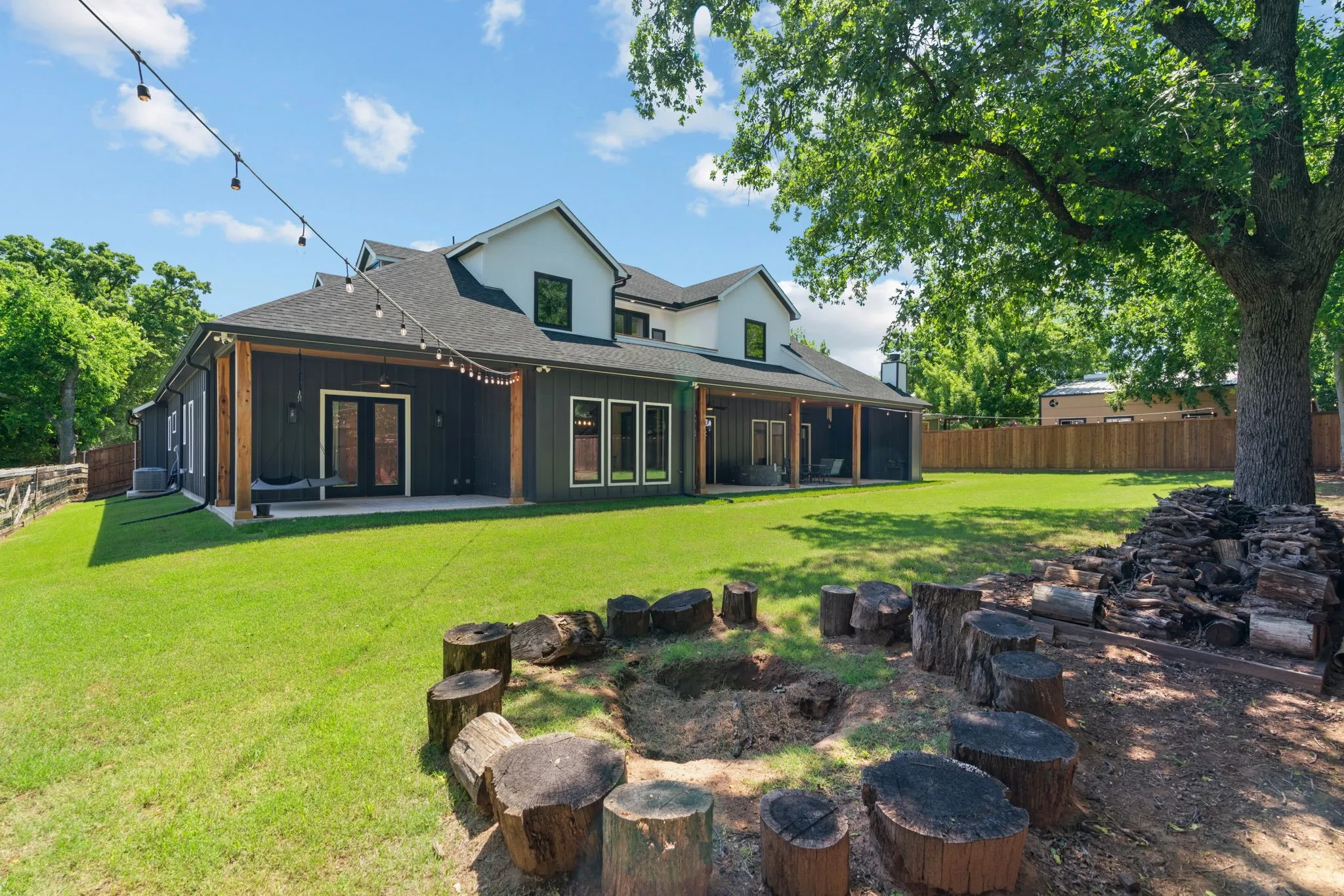 Expansive backyard featuring a large green lawn, perimeter fencing, and mature trees