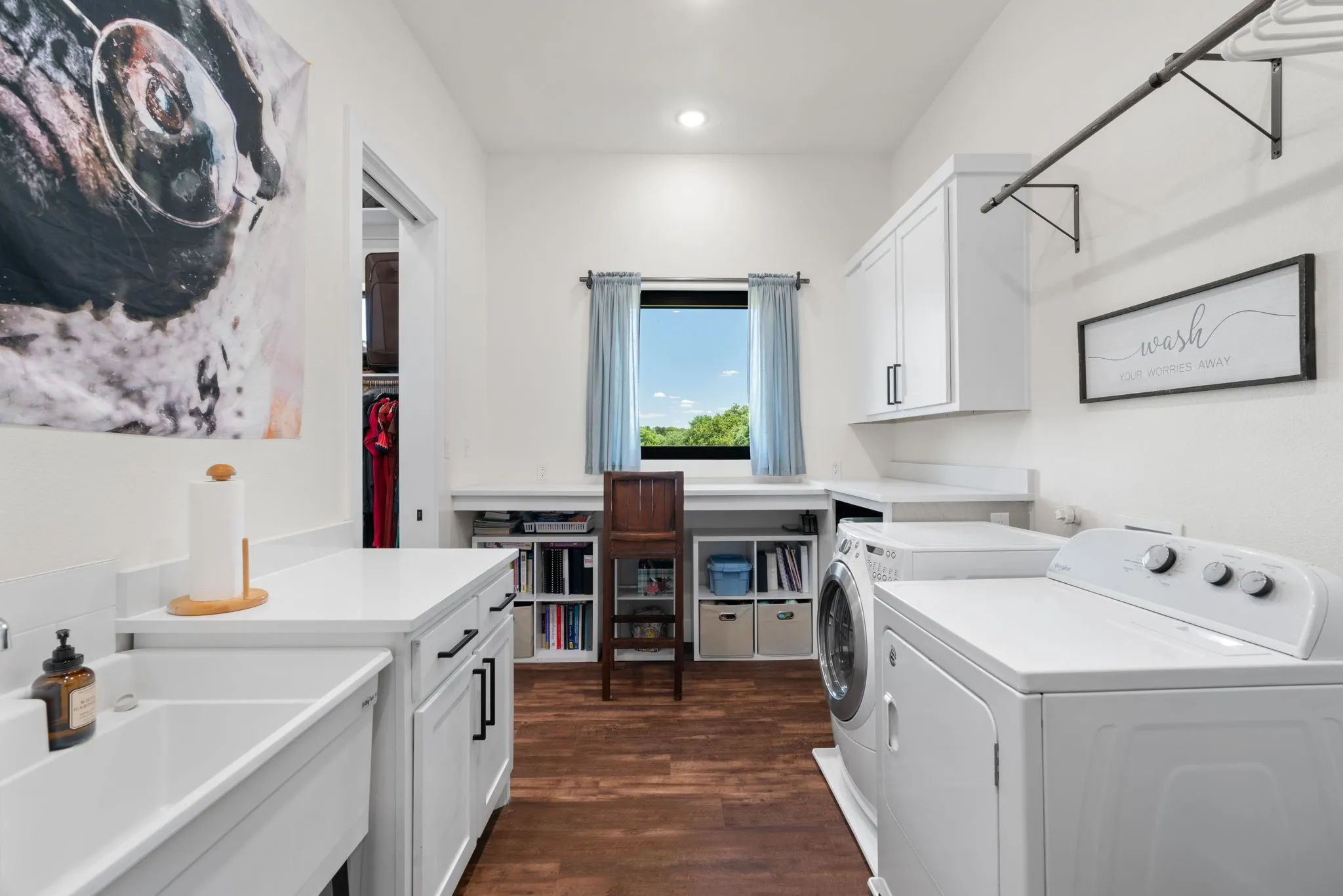 Dedicated utility room featuring wood-finish flooring, white cabinetry, and white countertops