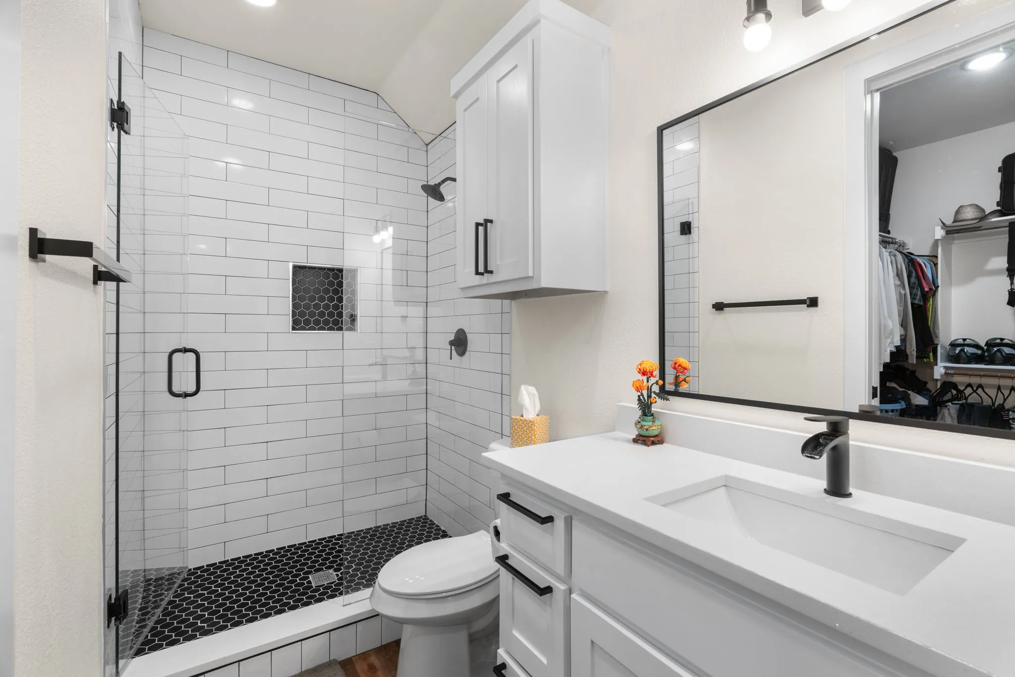 Modern bathroom featuring a frameless glass shower enclosure with subway tile walls and a hexagonal tile floor