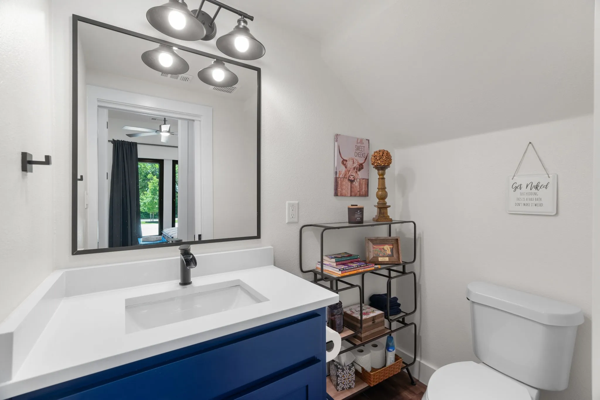 Bathroom featuring a blue vanity with a white countertop and integrated sink, a dark-framed mirror, and a three-bulb vanity light fixture