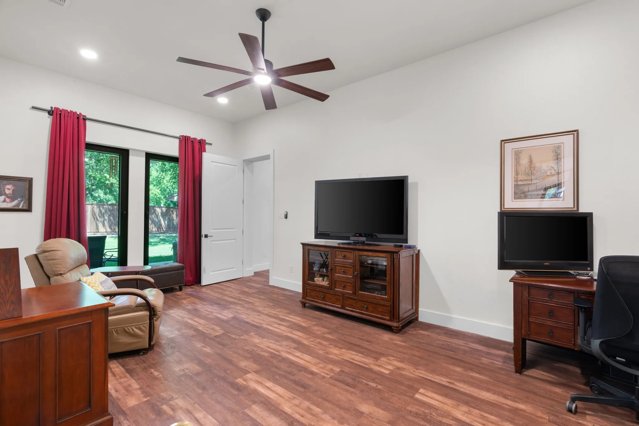 Spacious room featuring wood-finish flooring and a ceiling fan with integrated lighting