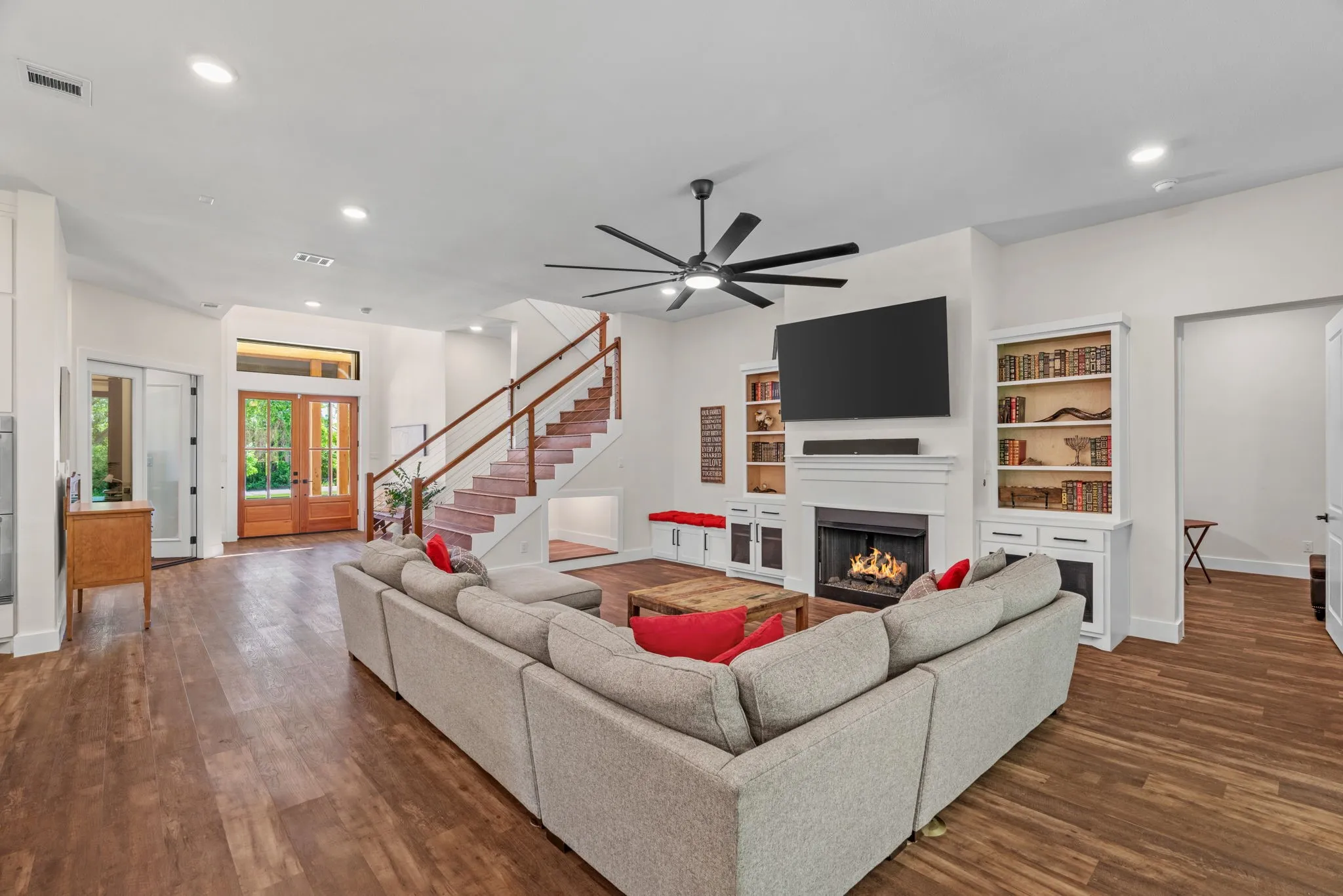 Spacious open-concept living area featuring wood-finish flooring, a contemporary ceiling fan, and recessed lighting
