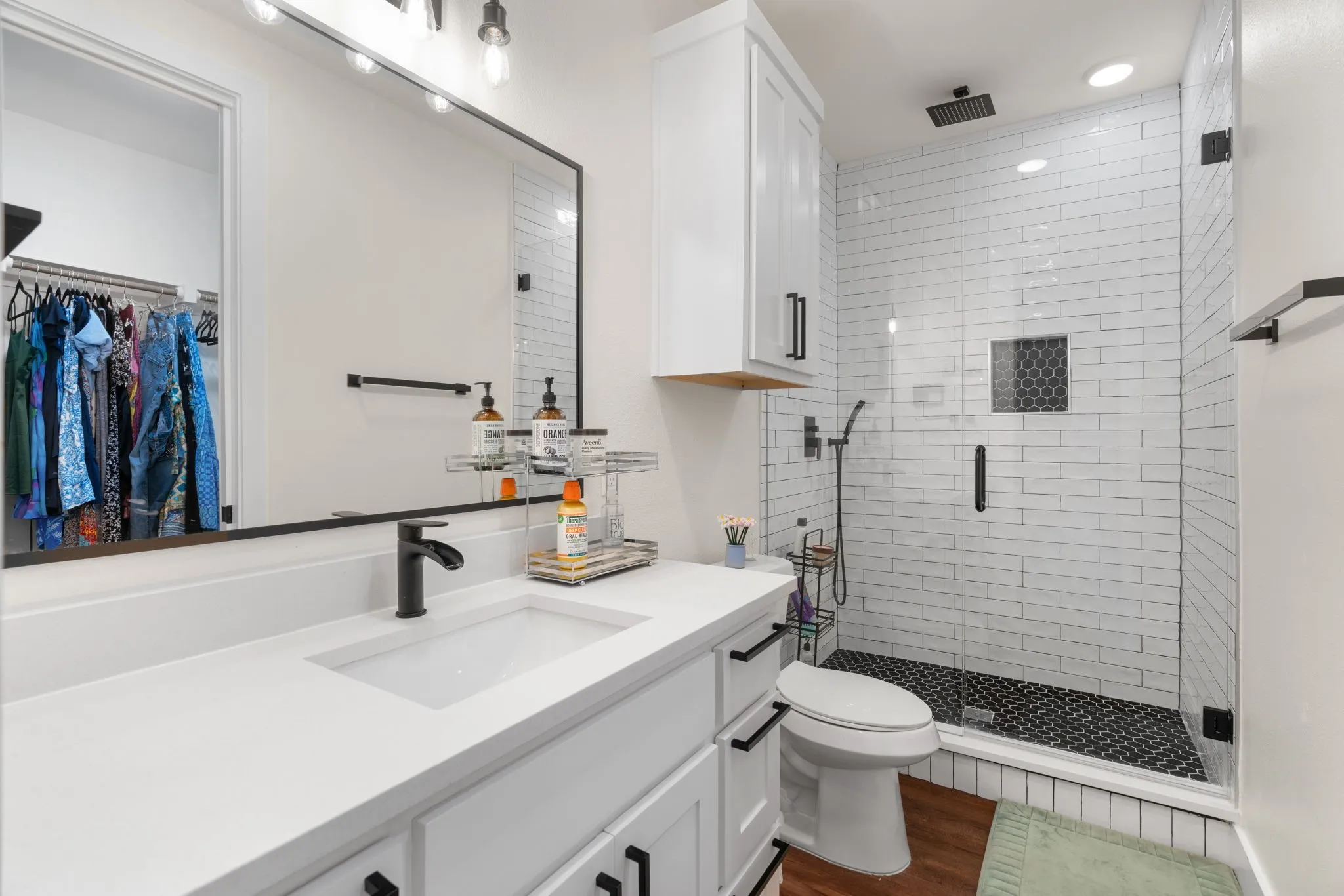 Contemporary bathroom featuring a spacious walk-in shower with white subway tile, dark hexagonal floor tiles, and a rainfall shower head