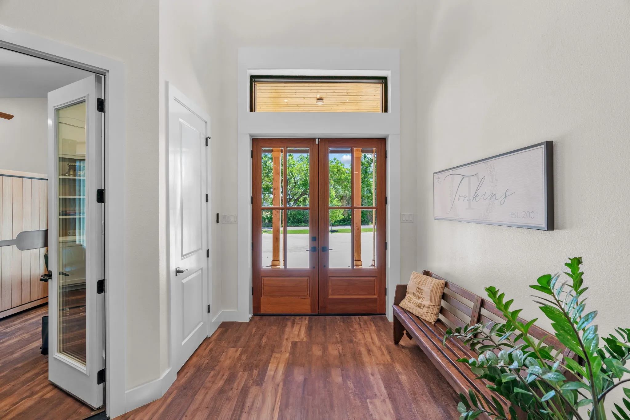 Entryway featuring wood-finish flooring, a double wood-paneled and glass door, and a transom window