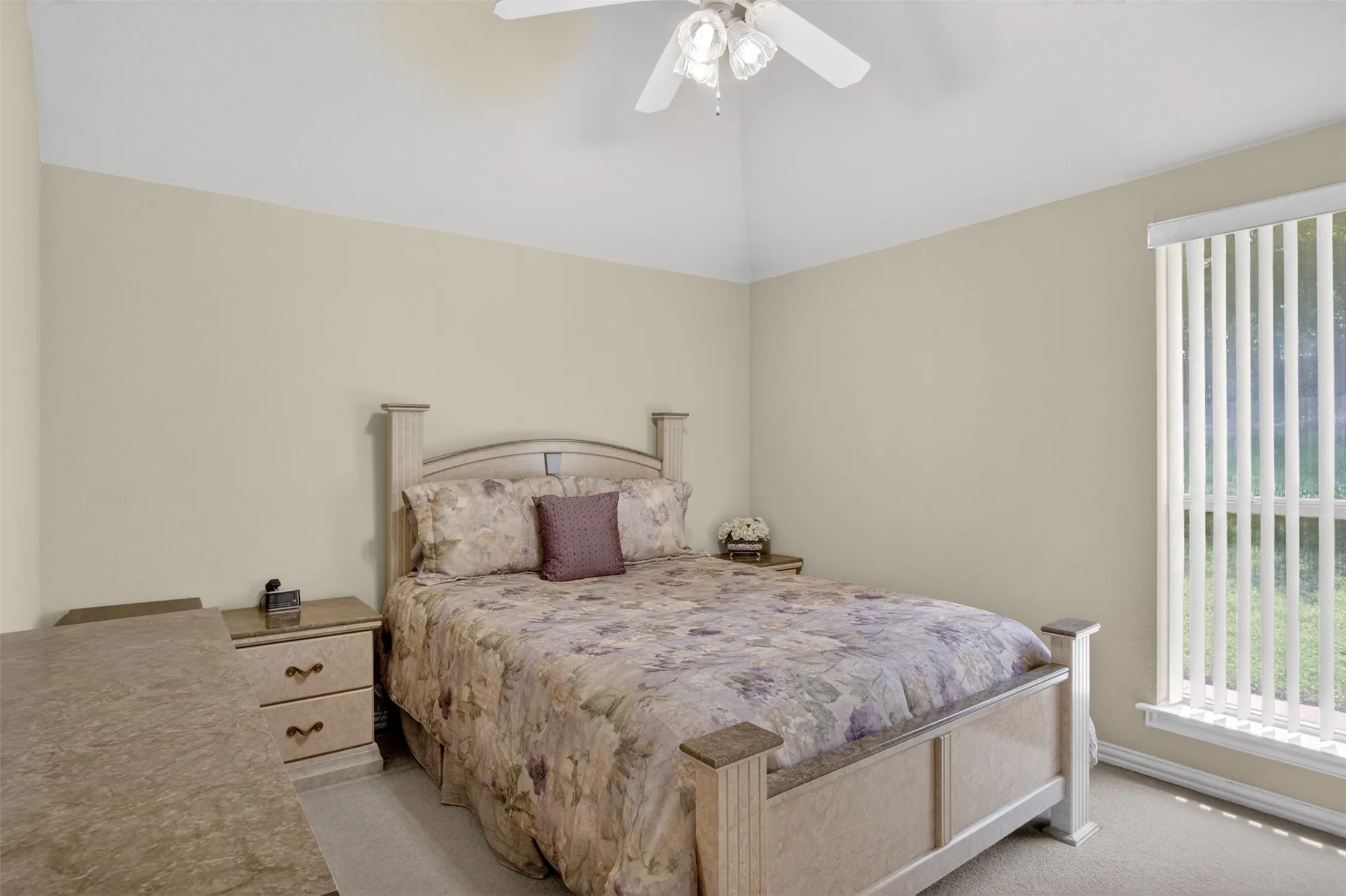 Vaulted ceiling with a ceiling fan light fixture, vertical blinds, and neutral-toned wall paint