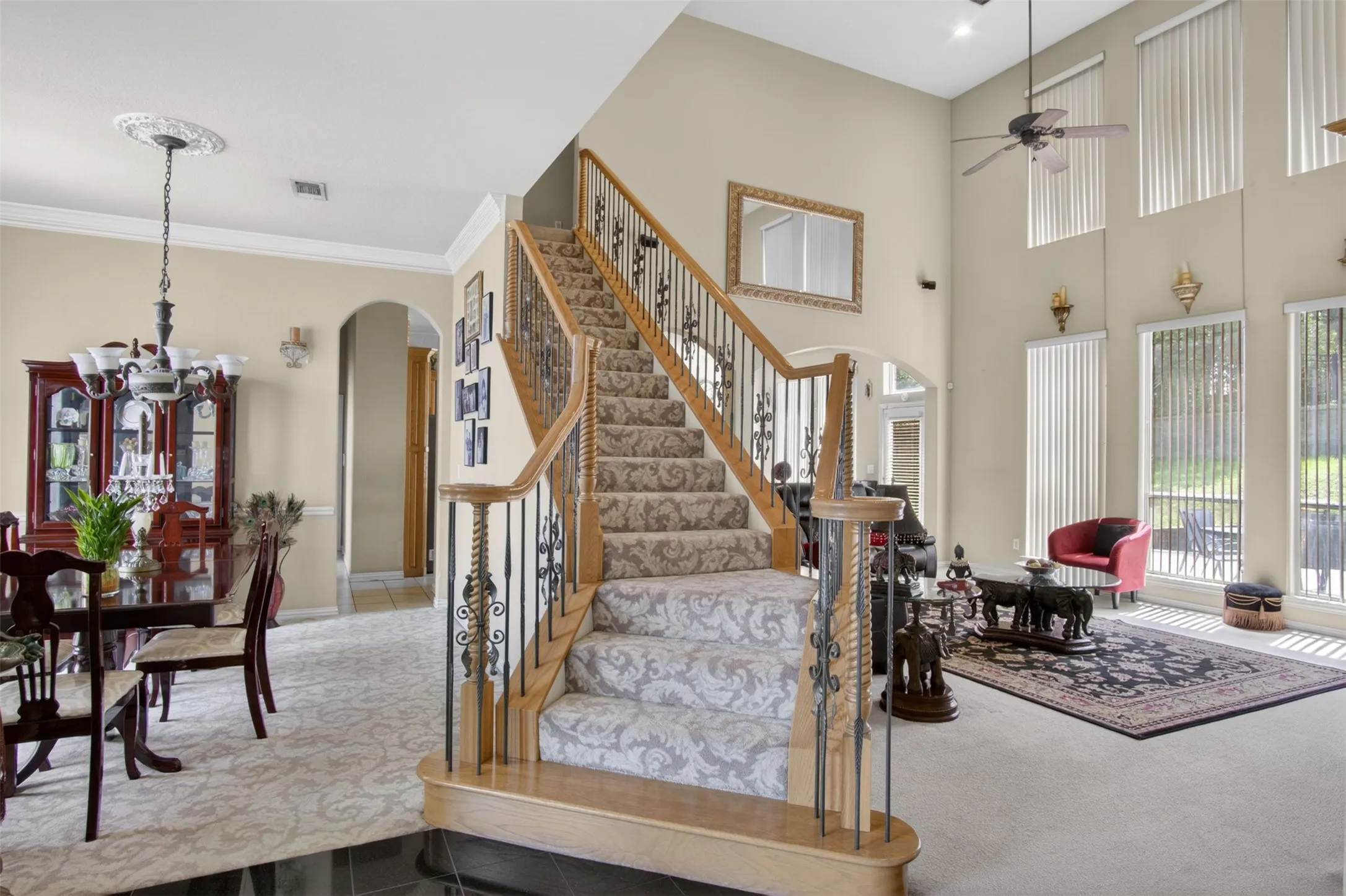 Two-story living area with a grand staircase featuring wood handrails and wrought iron balusters