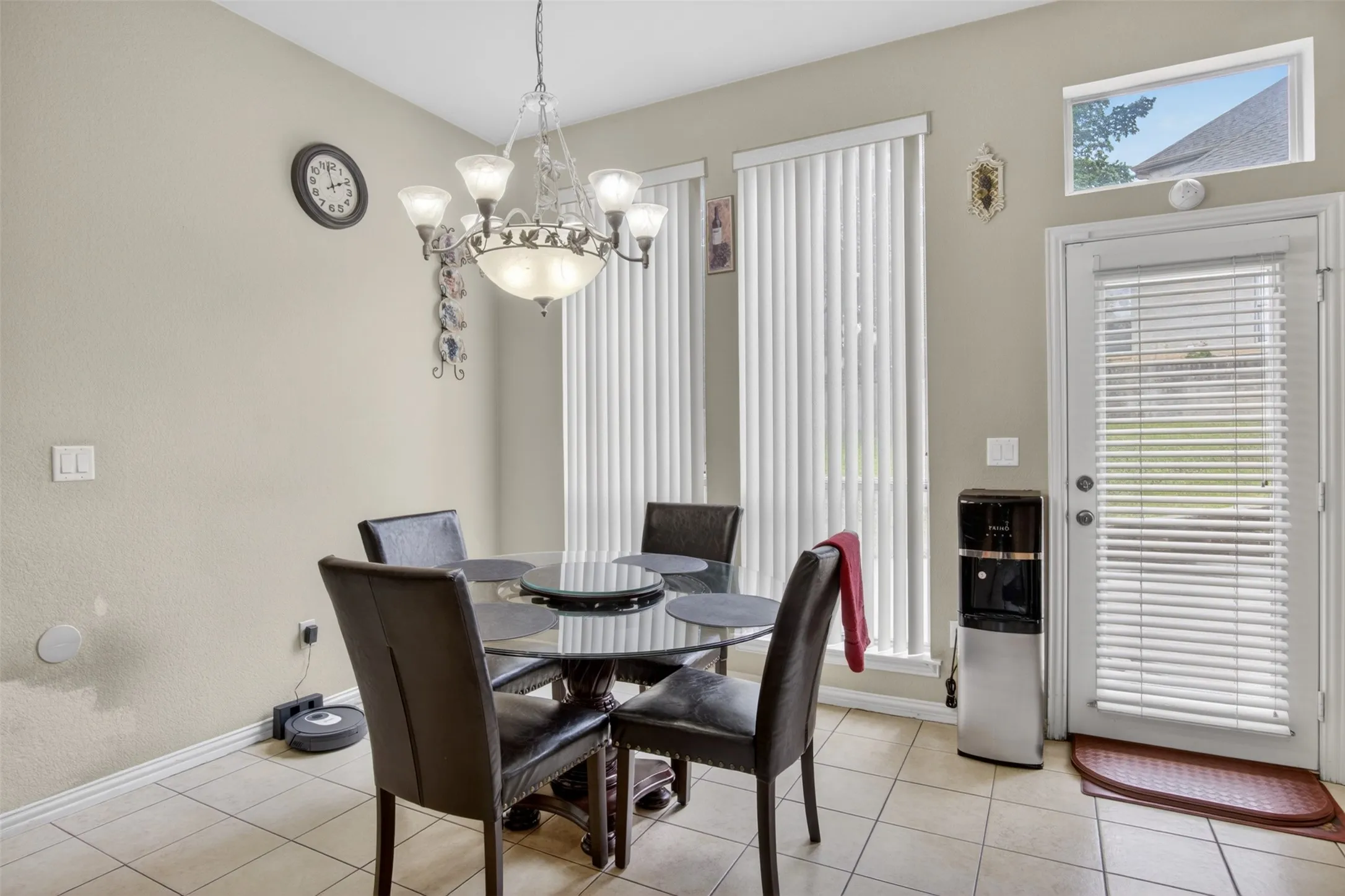 Dining area featuring a chandelier, tile flooring, and multiple windows with vertical blinds