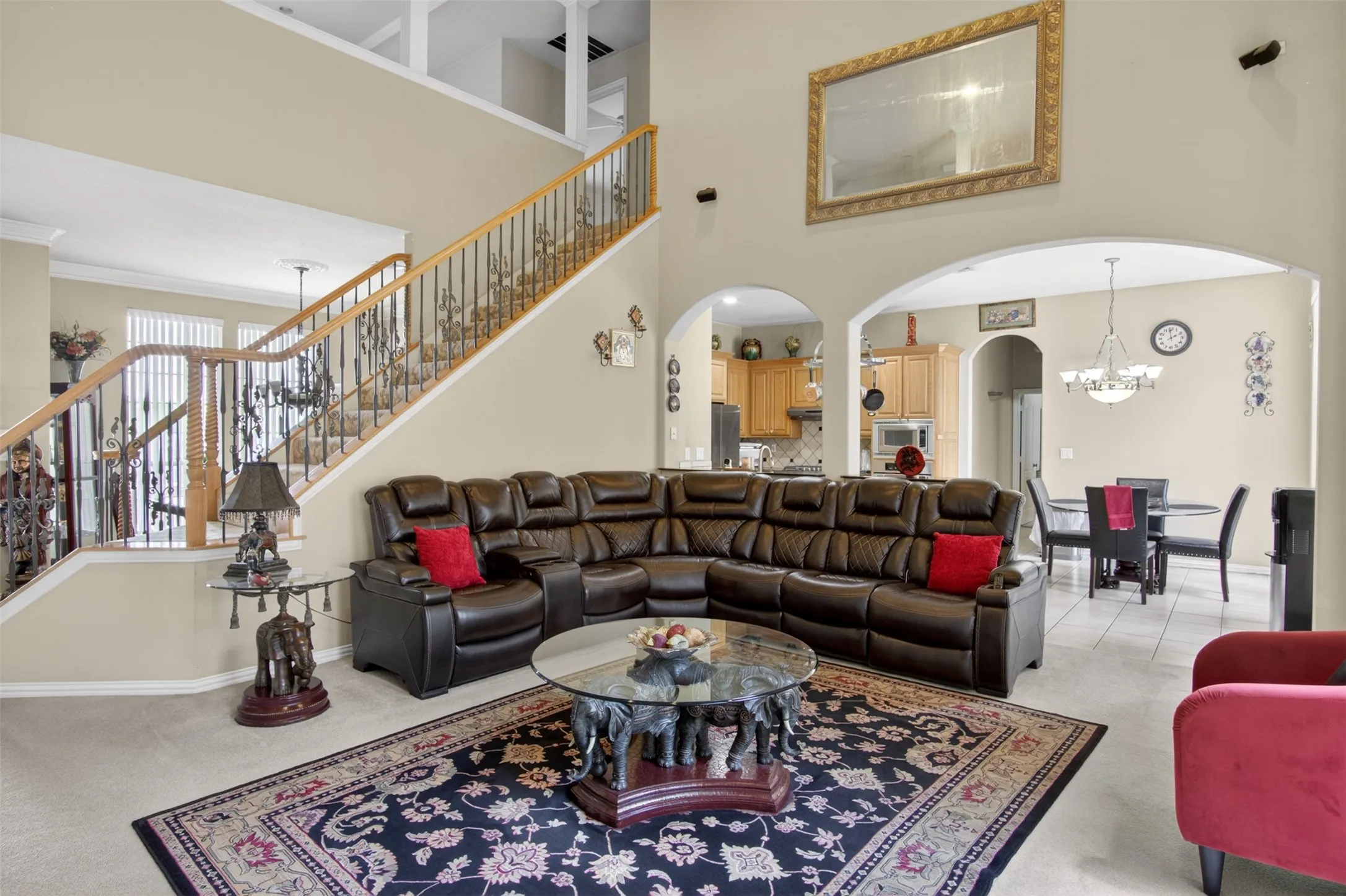 Vaulted living area featuring a two-story ceiling, arched doorways, a built-in staircase with wood railing and iron balusters, and neutral wall paint